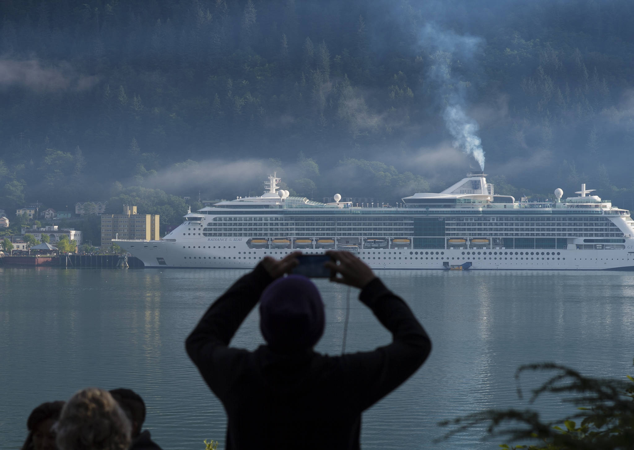 Michael Penn | Juneau Empire File                                A cruise ship passenger photographs a ship in Juneau’s downtown harbor in August 2017.