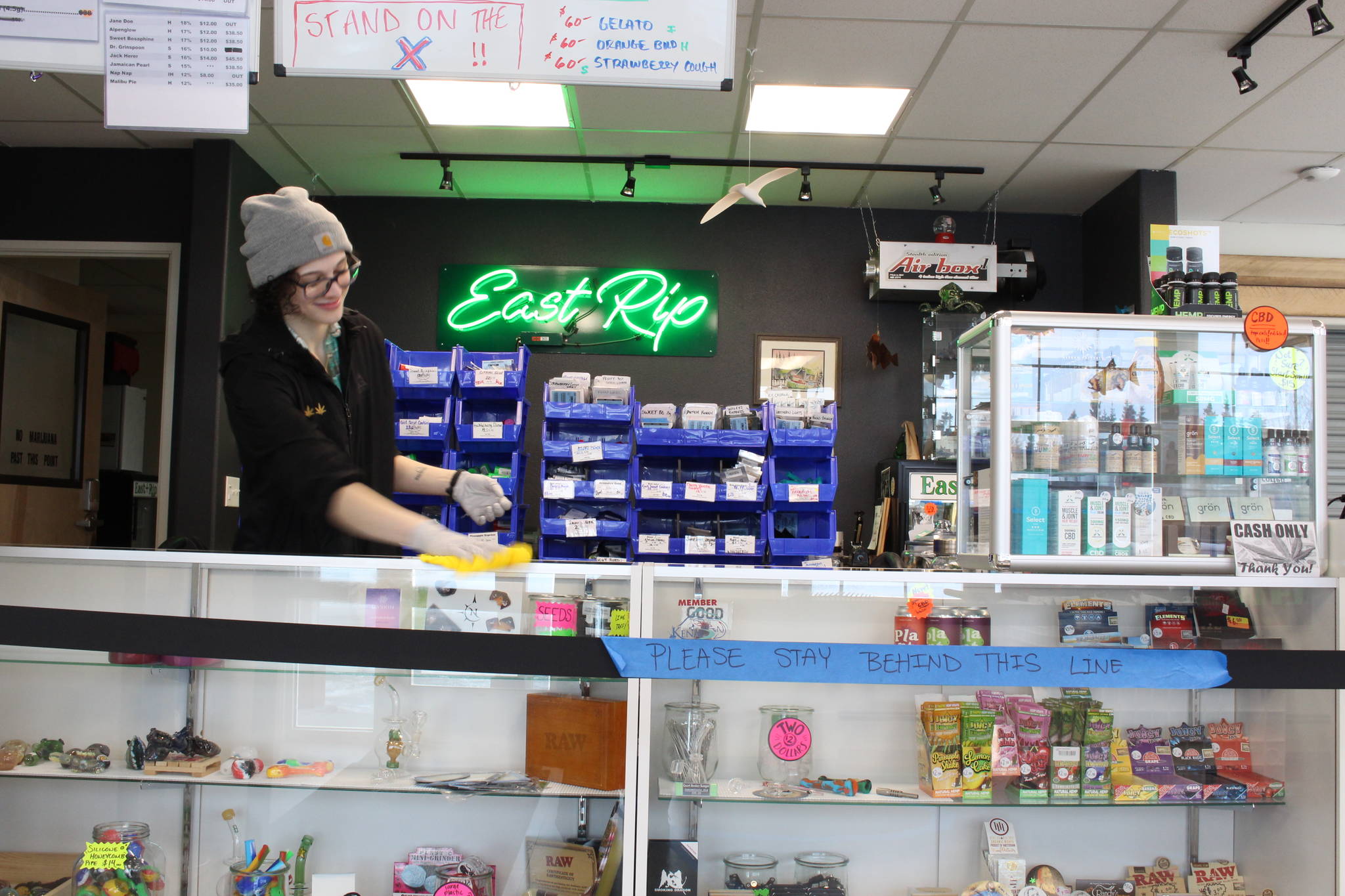 Mariah Schloeman wipes down the counter at East Rip in Kenai, Alaska on March 25, 2020. The store has implemented more stringent cleaning protocols, including wiping down surfaces after every transaction, in the wake of the coronavirus pandemic. (Photo by Brian Mazurek/Peninsula Clarion)