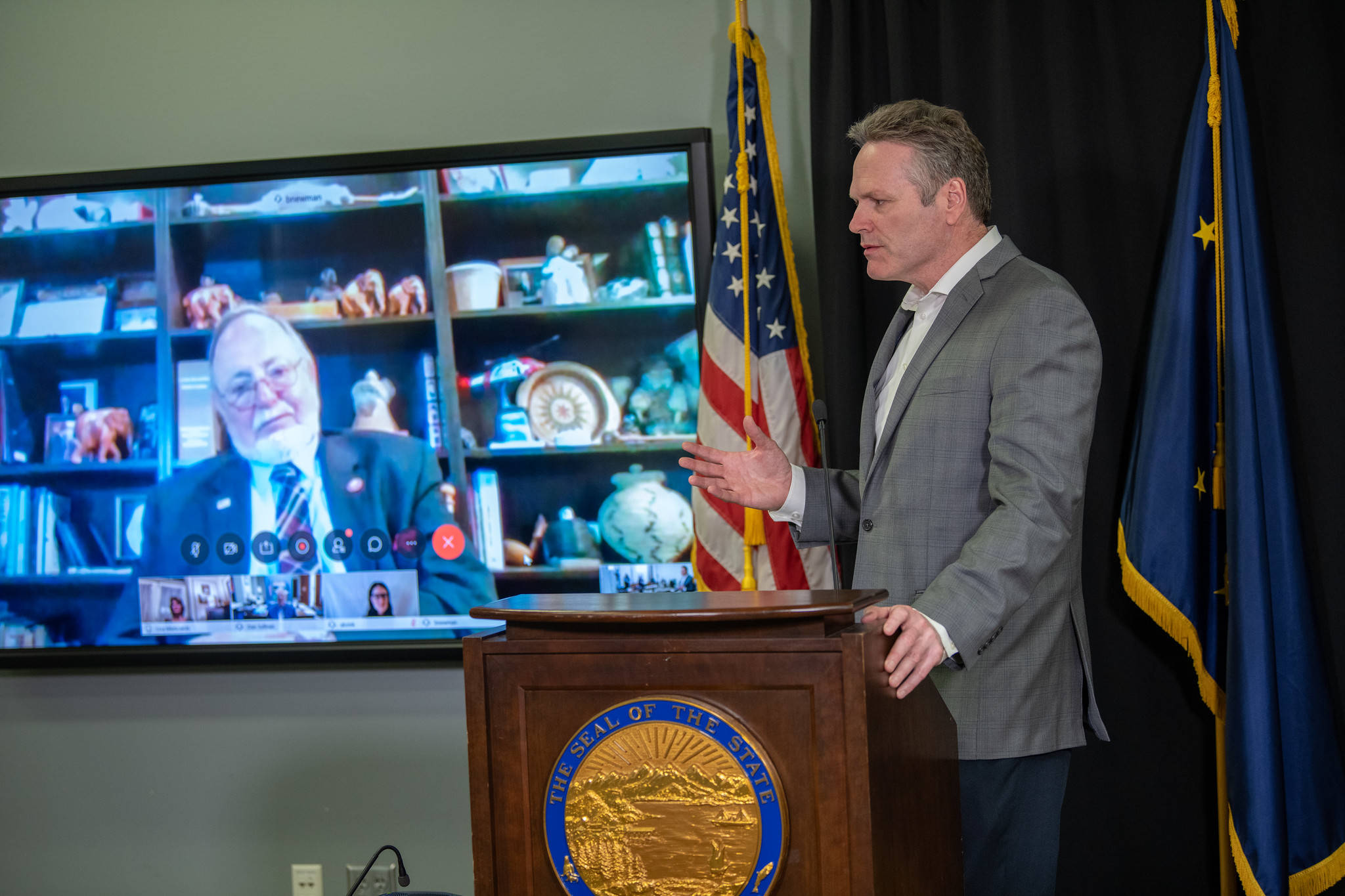 Gov. Mike Dunleavy speaks while Rep. Don Young, R-Alaska, looks on via a video feed at a press conference on March 30, 2020 in that Atwood Building in Anchorage, Alaska. (Photo courtesy Office of the Governor)