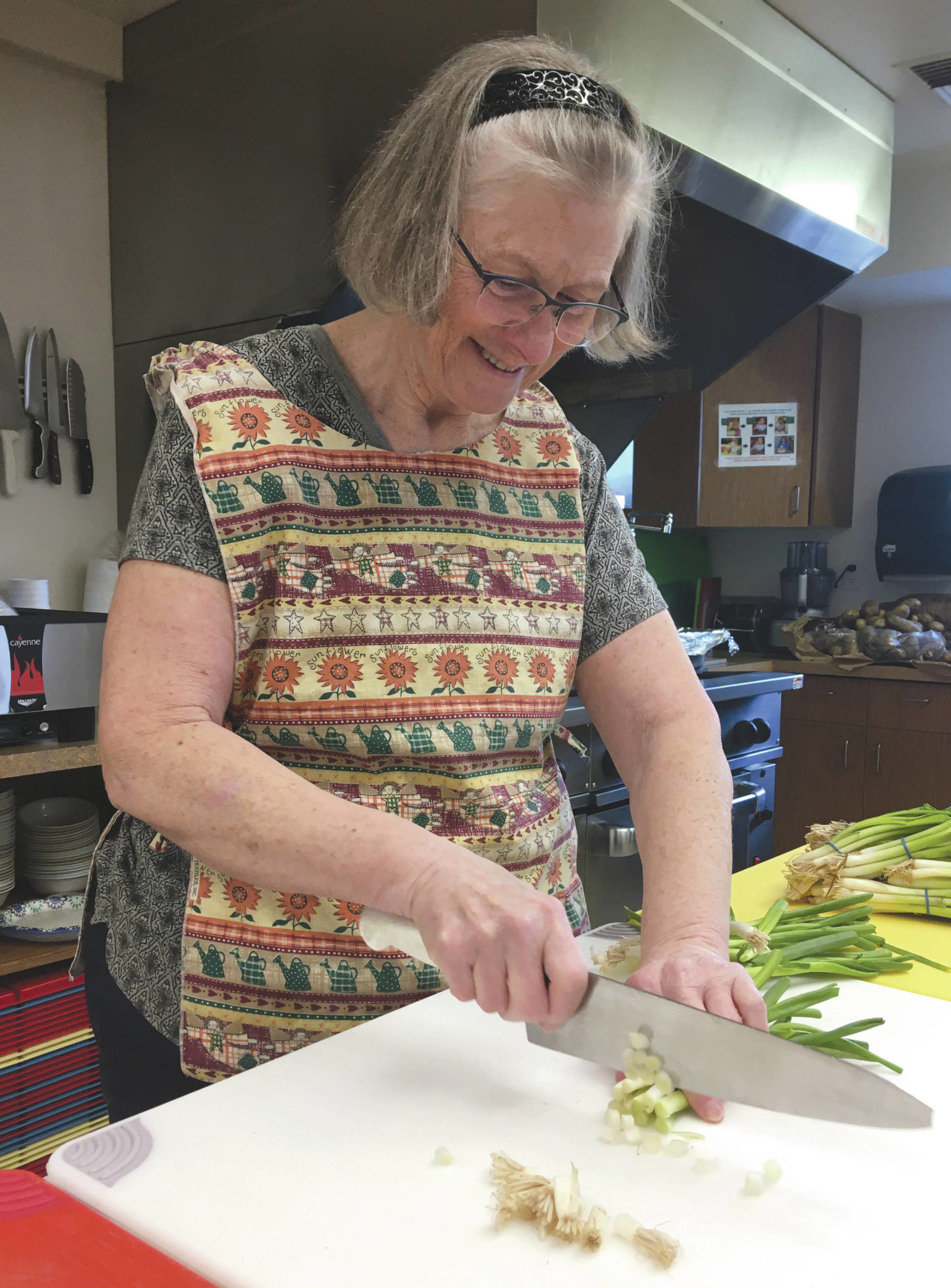 Jeff Helminiak / Peninsula Clarion                                Kasilof’s Cheryl Morse, a cook at the Kenai Peninsula Food Bank, chops up scallions for scalloped potatoes Tuesday at the food bank in Soldotna.