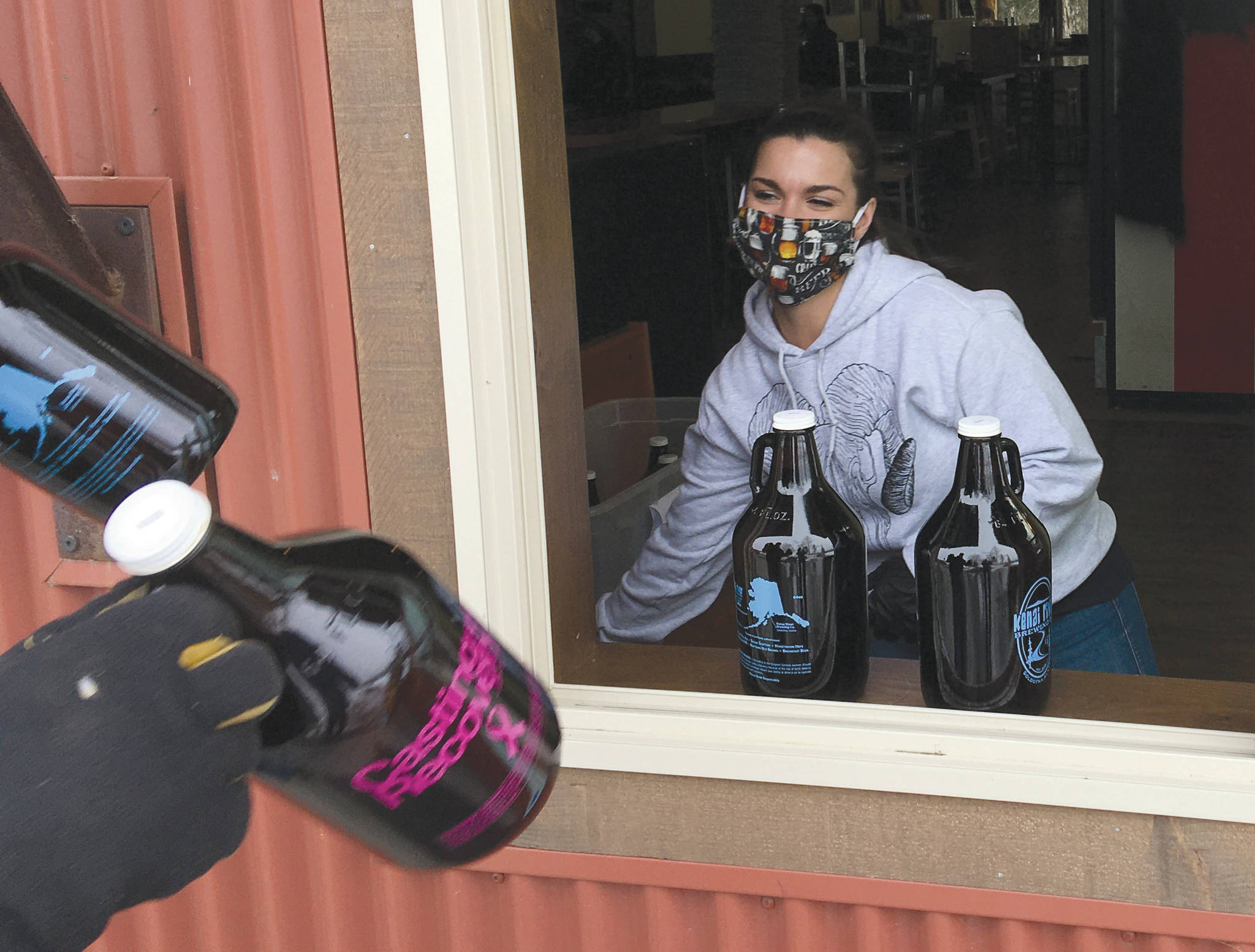 Jeff Helminiak | Peninsula Clarion                                Taleasha Shane of Soldotna swaps out growlers with a customer Tuesday at Kenai River Brewing in Soldotna. Shane has worked for the brewery for about four years and said business has been picking up in the last week. “The community is awesome. They’ve been tipping well. They know the servers are losing customers and money. It’s hard.”