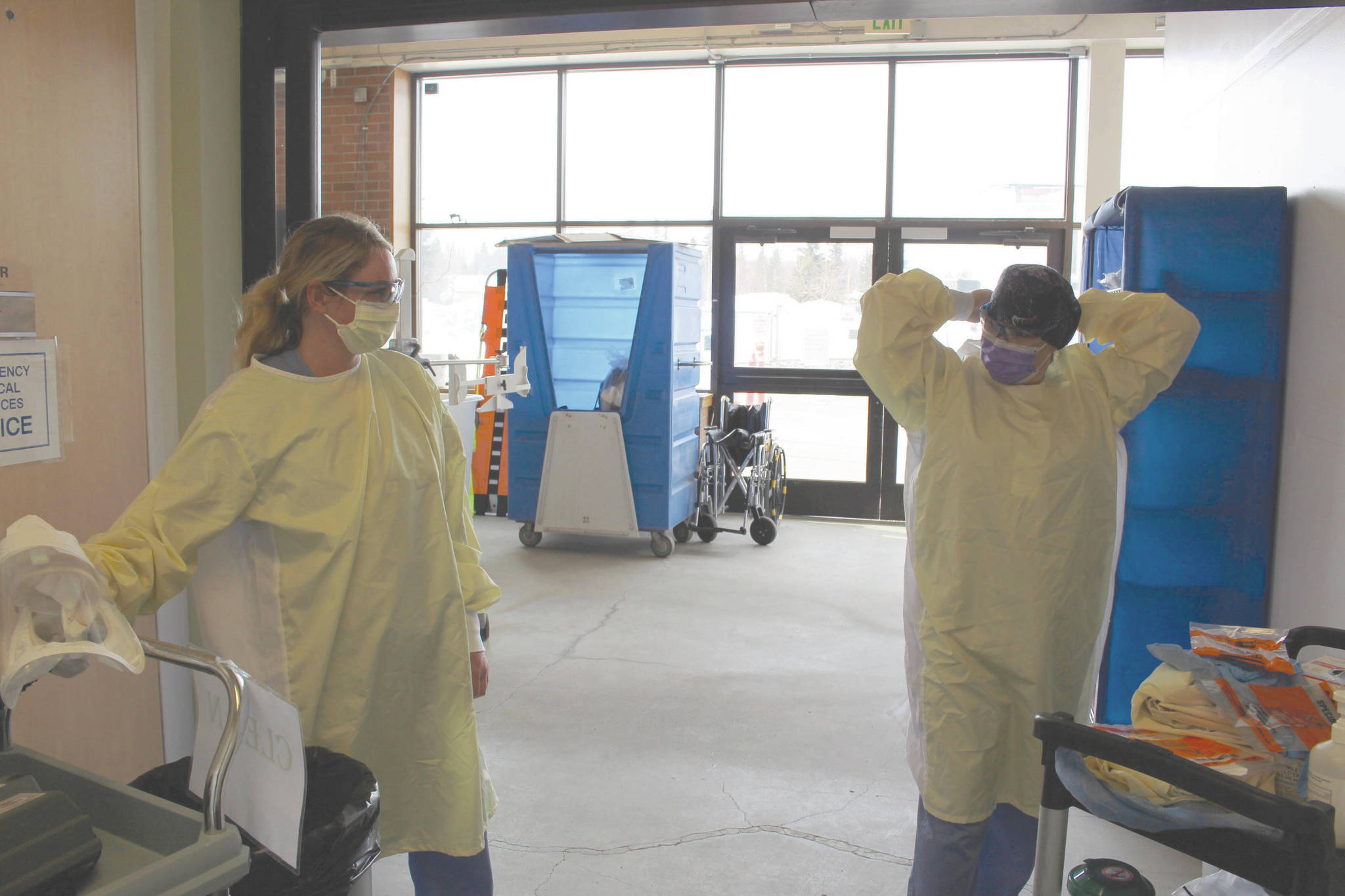 photos by Brian Mazurek / Peninsula Clarion                                Emergency room technician Angie Sulley (left) and nurse Marcie Duncan put on the personal protective equipment necessary for interacting with patients suspected of having COVID-19 in the ambulance bay outside of the emergency department at Central Peninsula Hospital in Soldotna on Tuesday.