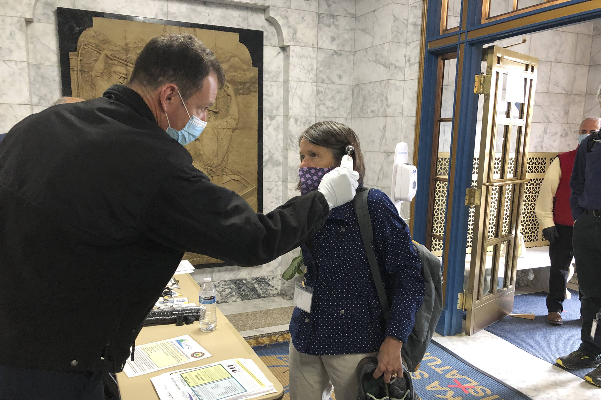 Alaska state Rep. Jennifer Johnston, an Anchorage Republican, gets her temperature taken by Roy Johnston, a captain with Capital City Fire/Rescue, at the state Capitol on Monday, May 18, 2020, in Juneau, Alaska. The Alaska Legislature planned to reconvene Monday to address use of federal coronavirus relief funds, with protocols in place aimed at guarding against the virus. (AP Photo/Becky Bohrer)