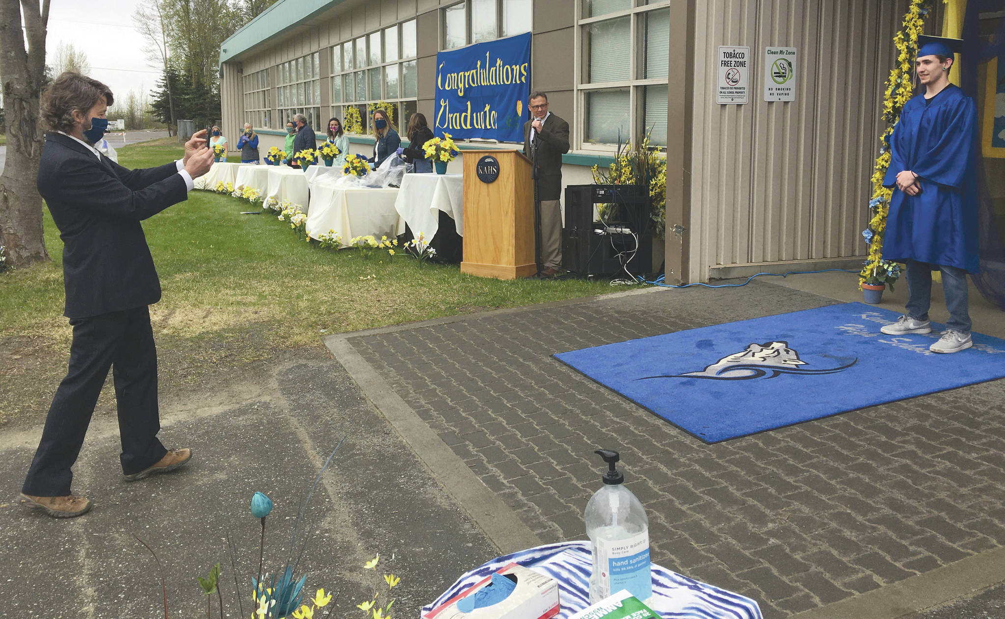 Jeff Helminiak / Peninsula Clarion                                 Kenai Alternative High School teacher Kevin Harding, retiring after 23 years with the Kenai Peninsula Borough School District and 22 with KAHS, takes a picture of graduate Robert Porter at the graduation ceremony Monday in Kenai, as Loren Reese, KAHS principal, announces.