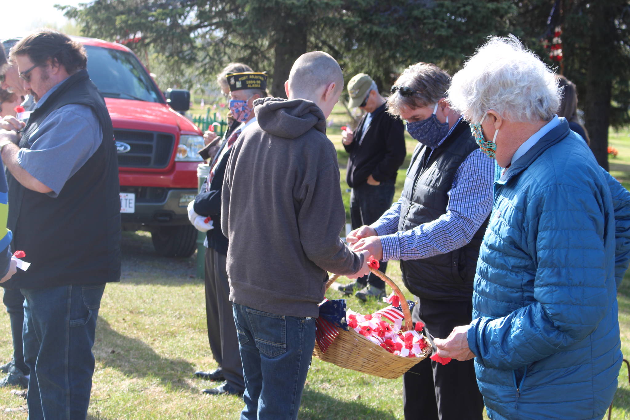 Kenai Mayor Brian Gabriel takes a poppy made by volunteers during the Memorial Day ceremony at the Kenai Cemetery on May 25, 2020. (Photo by Brian Mazurek/Peninsula Clarion)
