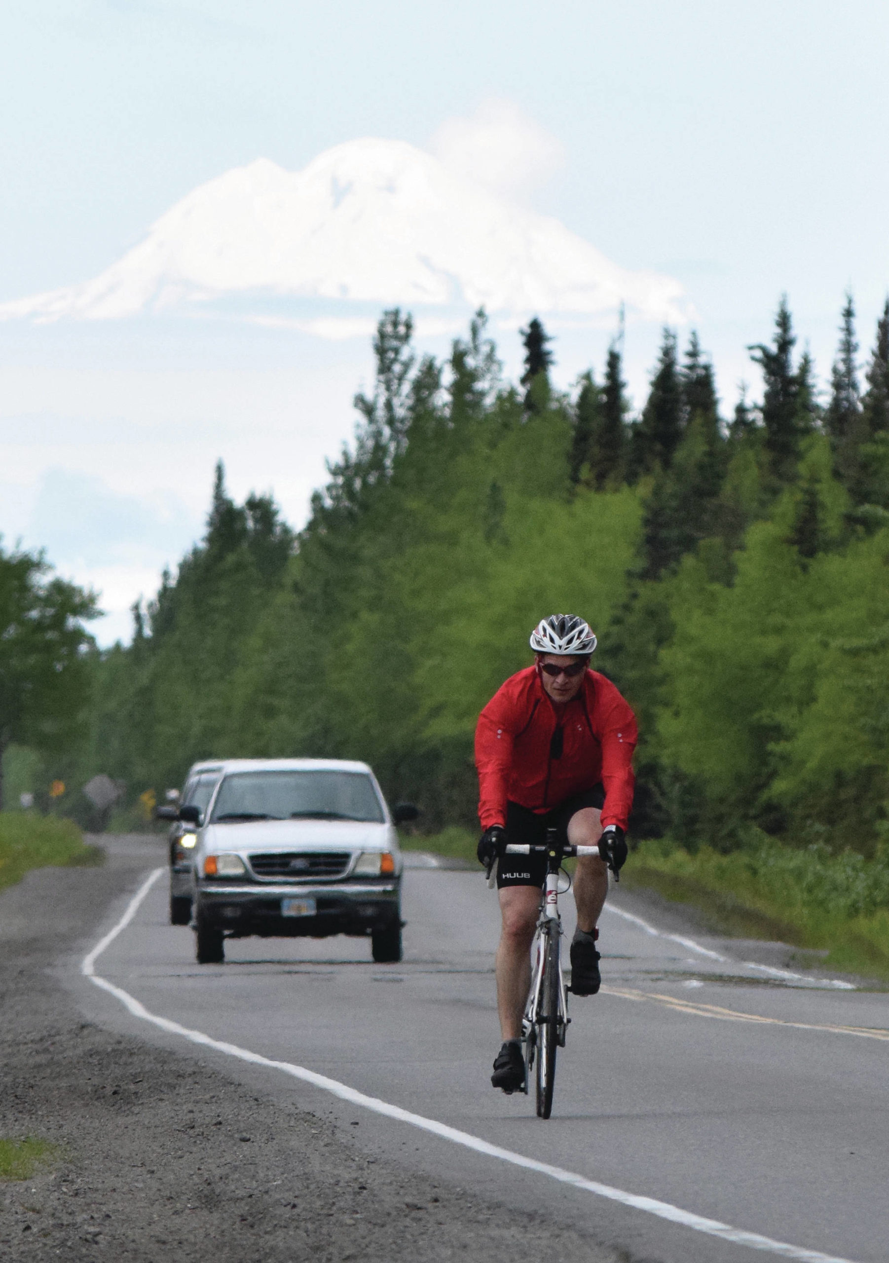 Joey Klecka / Peninsula Clarion                                Anchorage’s John Krellner rides down Gas Well Road with Mount Redoubt in the background June 9, 2019, in the Tri-The-Kenai Triathlon in Soldotna.