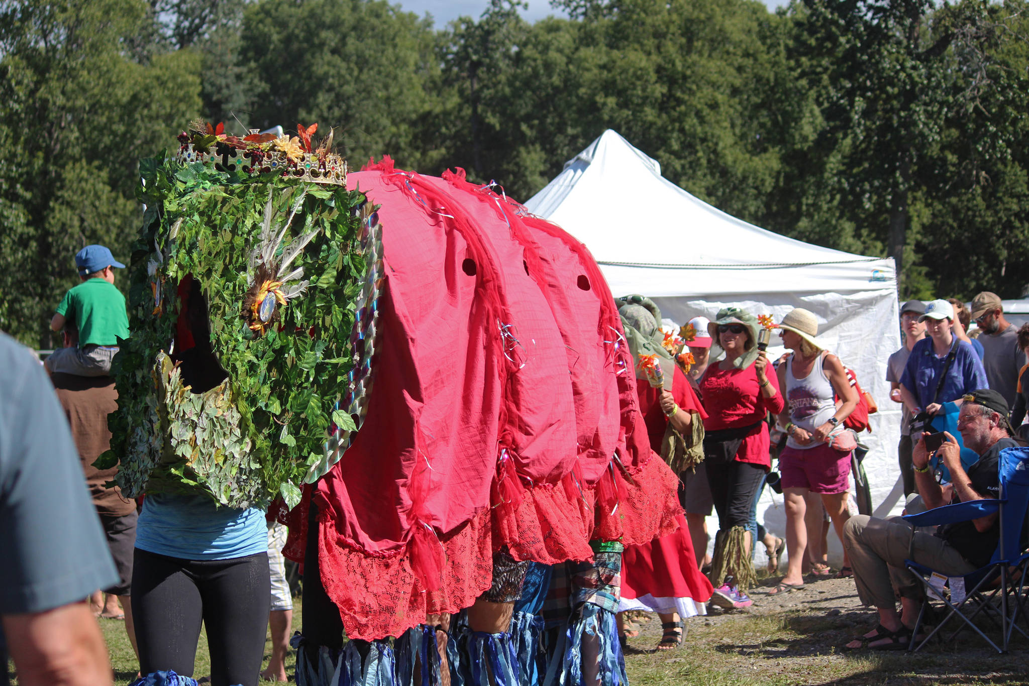 Participants in an aerial art installation march through the Kenai Peninsula Fairgrounds, with a king salmon leading the way, at Salmonfest in Ninilchik.