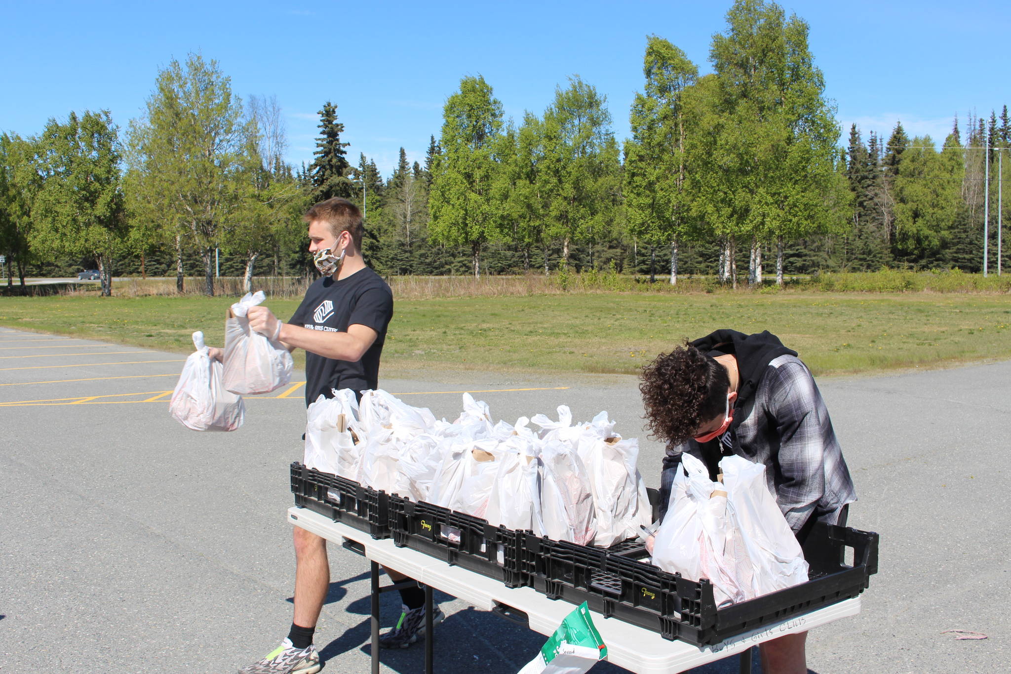 Kenai Peninsula Boys & Girls Clubs employees Michael Eiter, left, and Michael Mysing, right, hand out meals at Kenai Central High School in Kenai, Alaska on May 28, 2020. (Photo by Brian Mazurek/Peninsula Clarion)