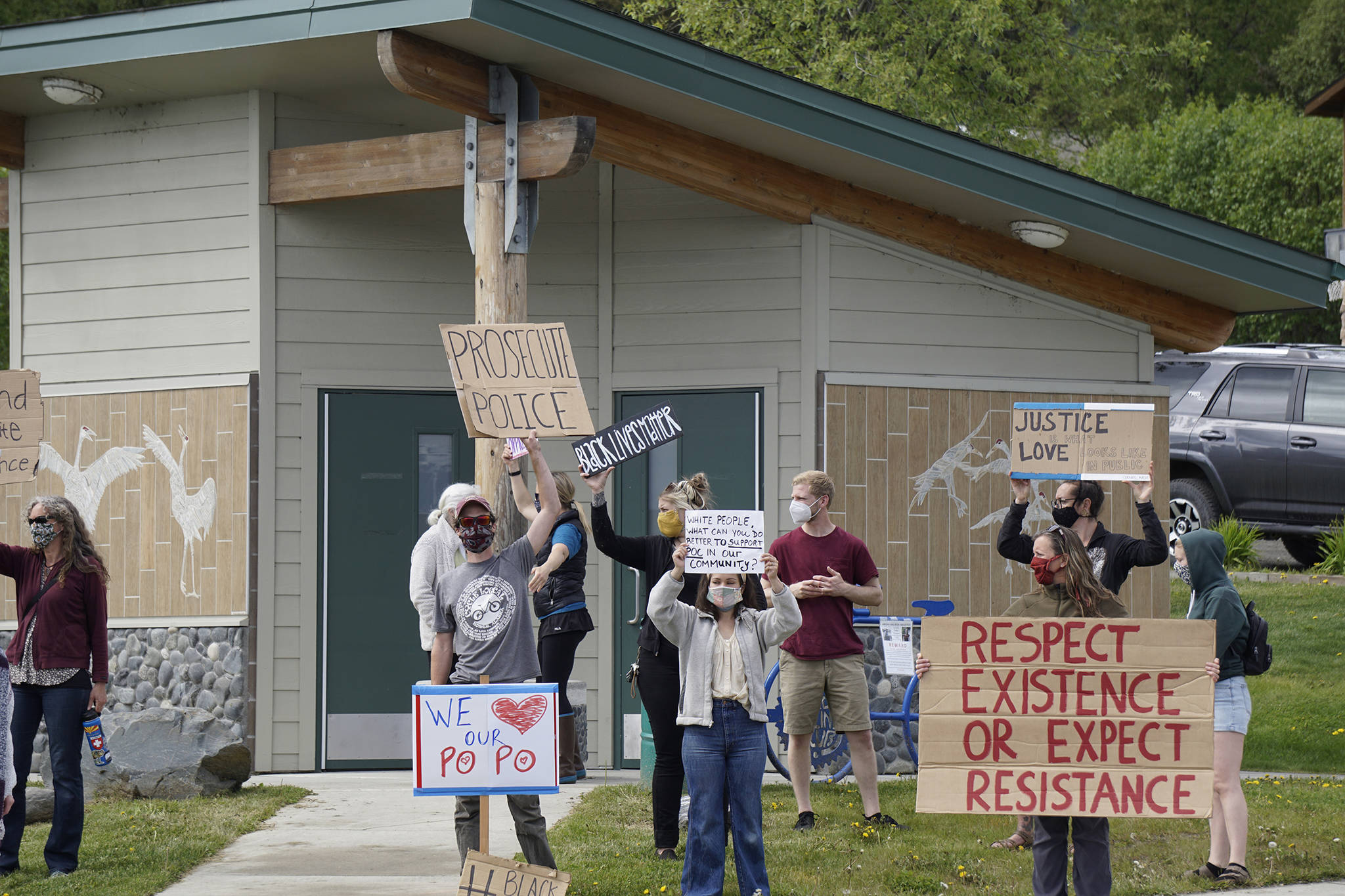 In front and from left to right, Aaron Ford, Karianna Ford and Jenni Stowe hold signs at a protest on Sunday, May 30, 2020, at WKFL Park in Homer, Alaska, in support of people of color who have been the subject of police violence, including George Floyd, a man who died May 25, 2020, in a police encounter in Minneapolis, Minnesota. In addition to the “We (heart) our po po” sign — “po po” is slang for “police” — there also was a sign that read “Thank you HPD.” (Photo by Michael Armstrong/Homer News)