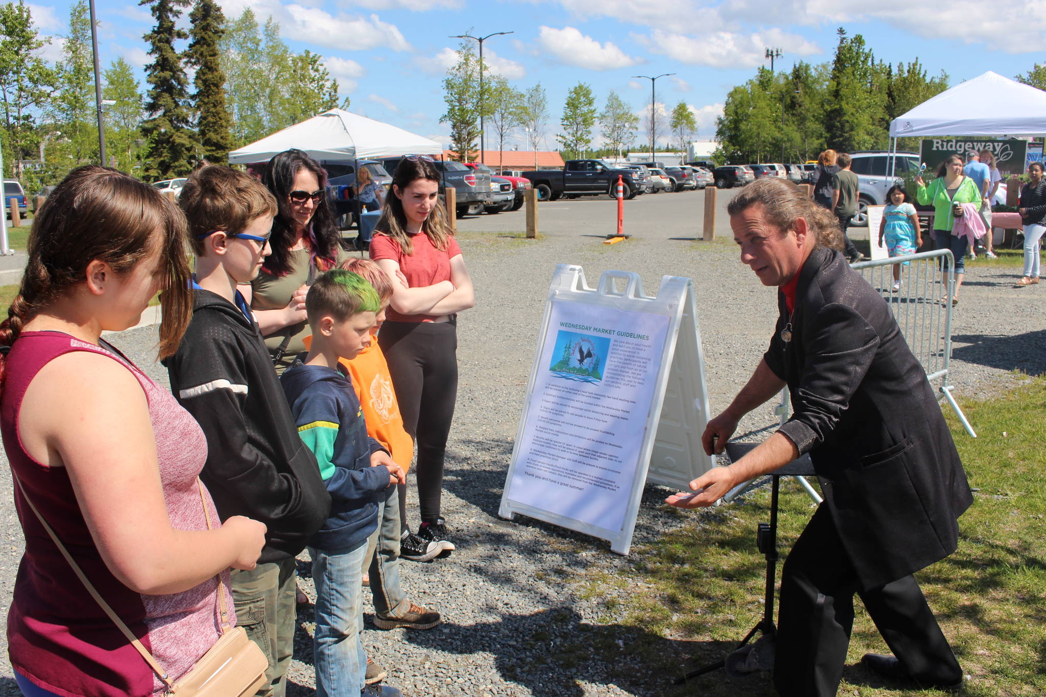 Magician Jungle Josh, right, performs for a small crowd of onlookers during the Wednesday Market at Soldotna Creek Park in Soldotna, Alaska on June 10, 2020. (Photo by Brian Mazurek/Peninsula Clarion)