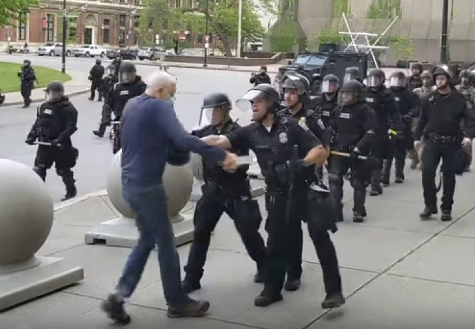 In this image from video provided by WBFO, a Buffalo police officer appears to shove a man who walked up to police Thursday, June 4, 2020, in Buffalo, N.Y. Video from WBFO shows the man appearing to hit his head on the pavement, with blood leaking out as officers walk past to clear Niagara Square. Buffalo police initially said in a statement that a person “was injured when he tripped & fell,” WIVB-TV reported, but Capt. Jeff Rinaldo later told the TV station that an internal affairs investigation was opened. Police Commissioner Byron Lockwood suspended two officers late Thursday, the mayor’s statement said. (Mike Desmond | WBFO via AP)