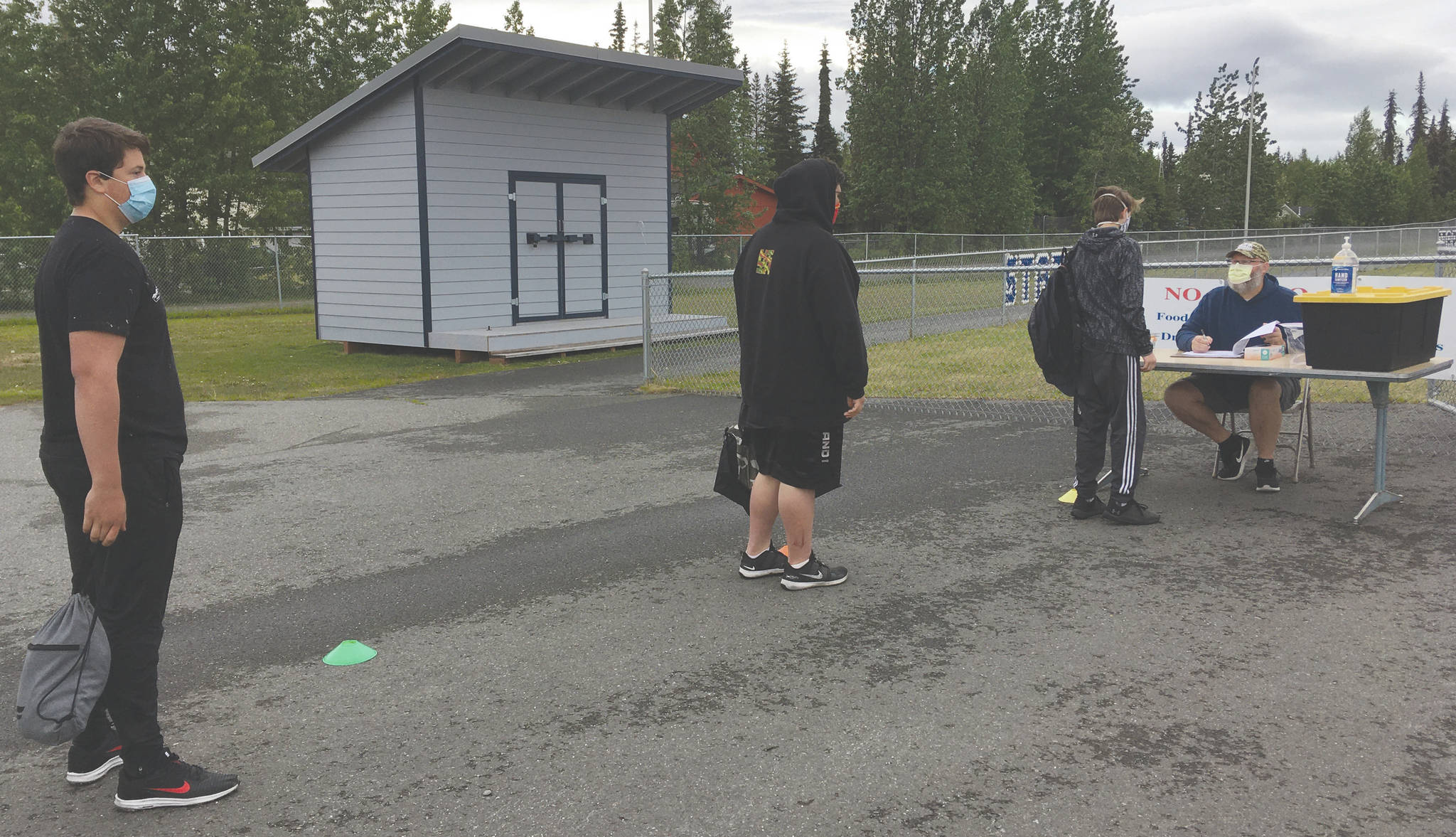 Soldotna football players wait in line to get screened by head coach Galen Brantley Jr. before summer workouts Wednesday, June 17, 2020, at Soldotna High School in Soldotna, Alaska. (Photo by Jeff Helminiak/Peninsula Clarion)