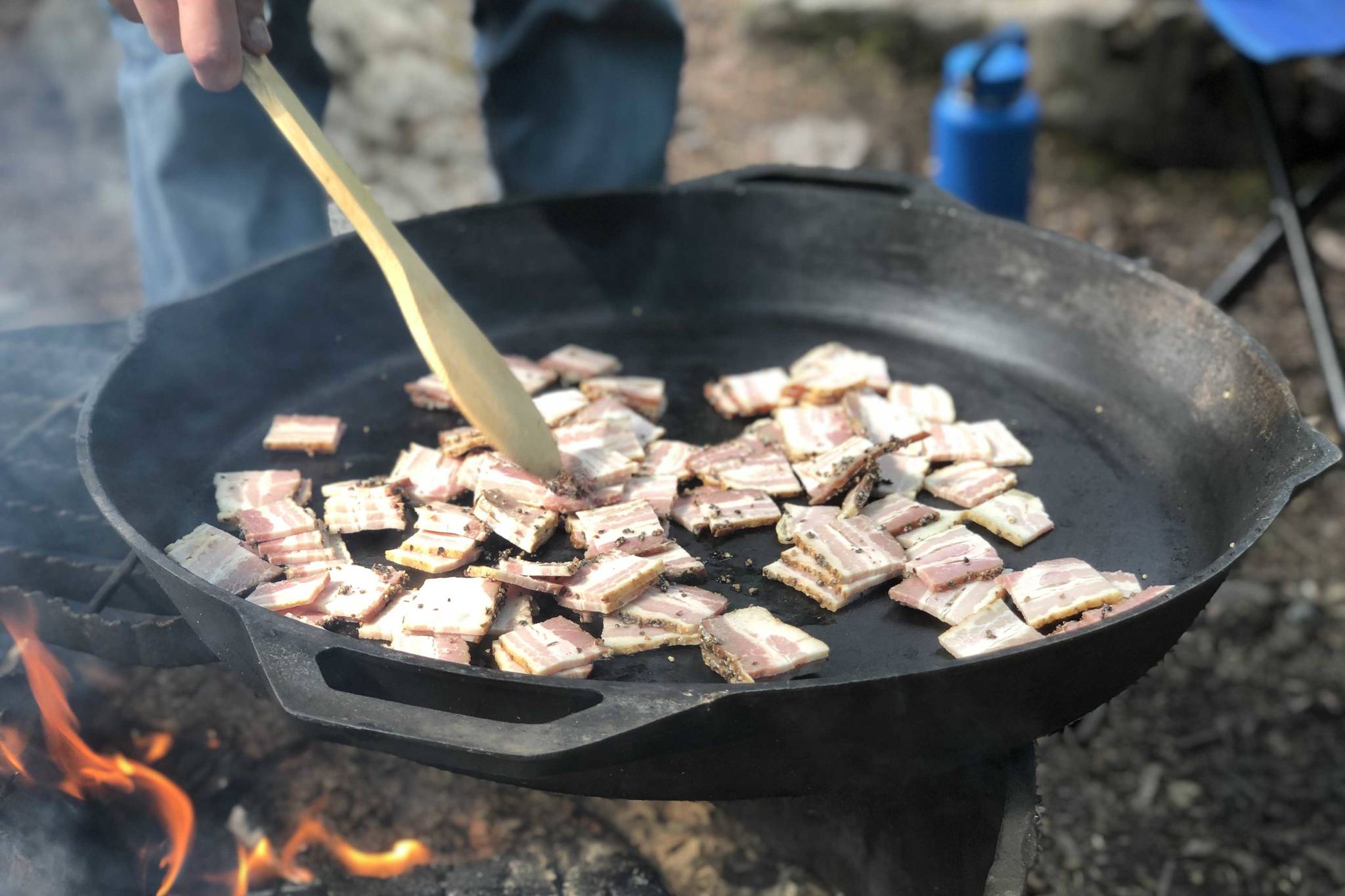 Bacon is prepared on a fire pit, June 19, 2020, in the Copper River Valley, Alaska. (Photo by Victoria Petersen/Peninsula Clarion)