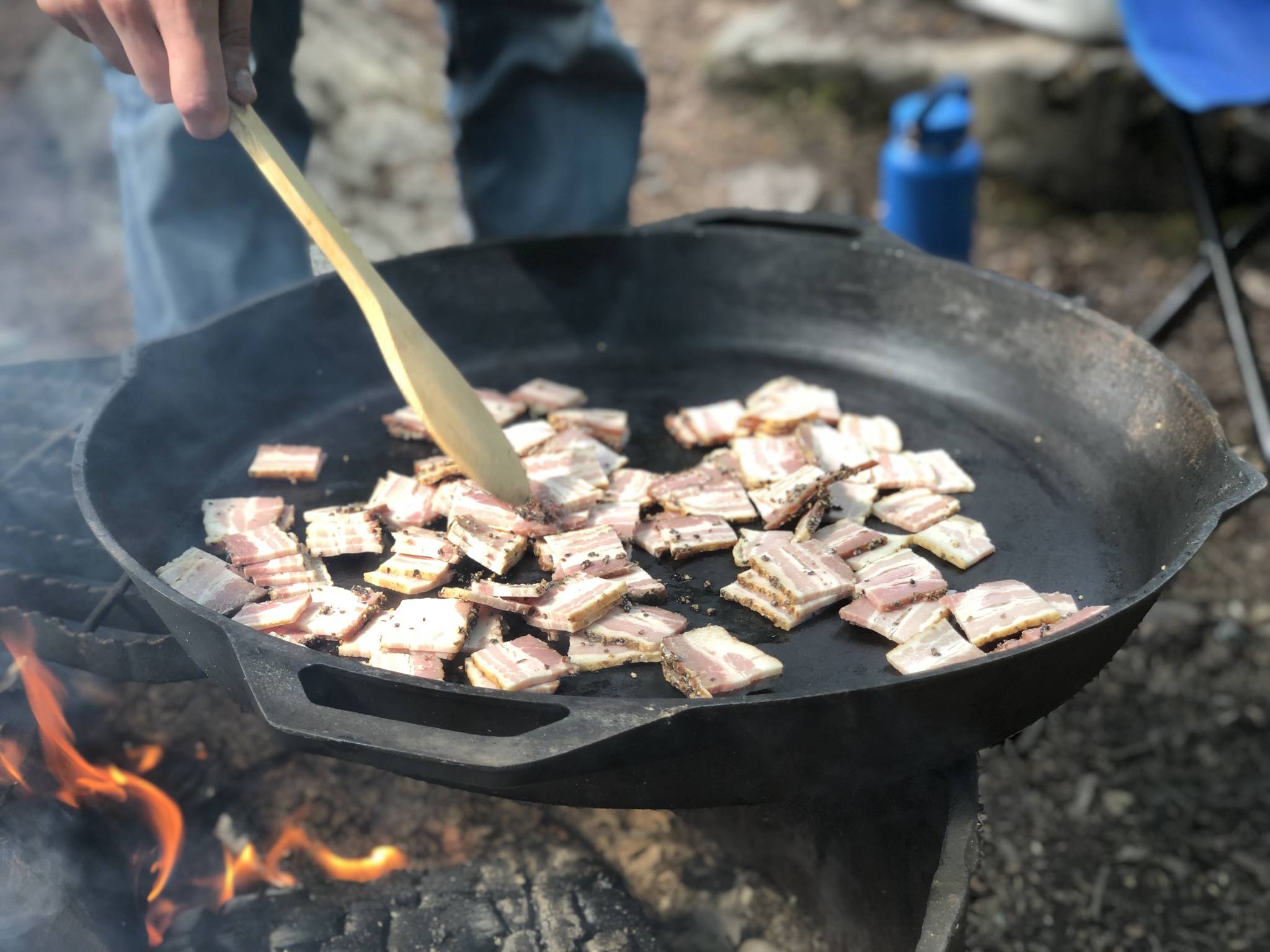 Bacon is prepared on a fire pit, June 19, in the Copper River Valley. (Photo by Victoria Petersen/Peninsula Clarion)