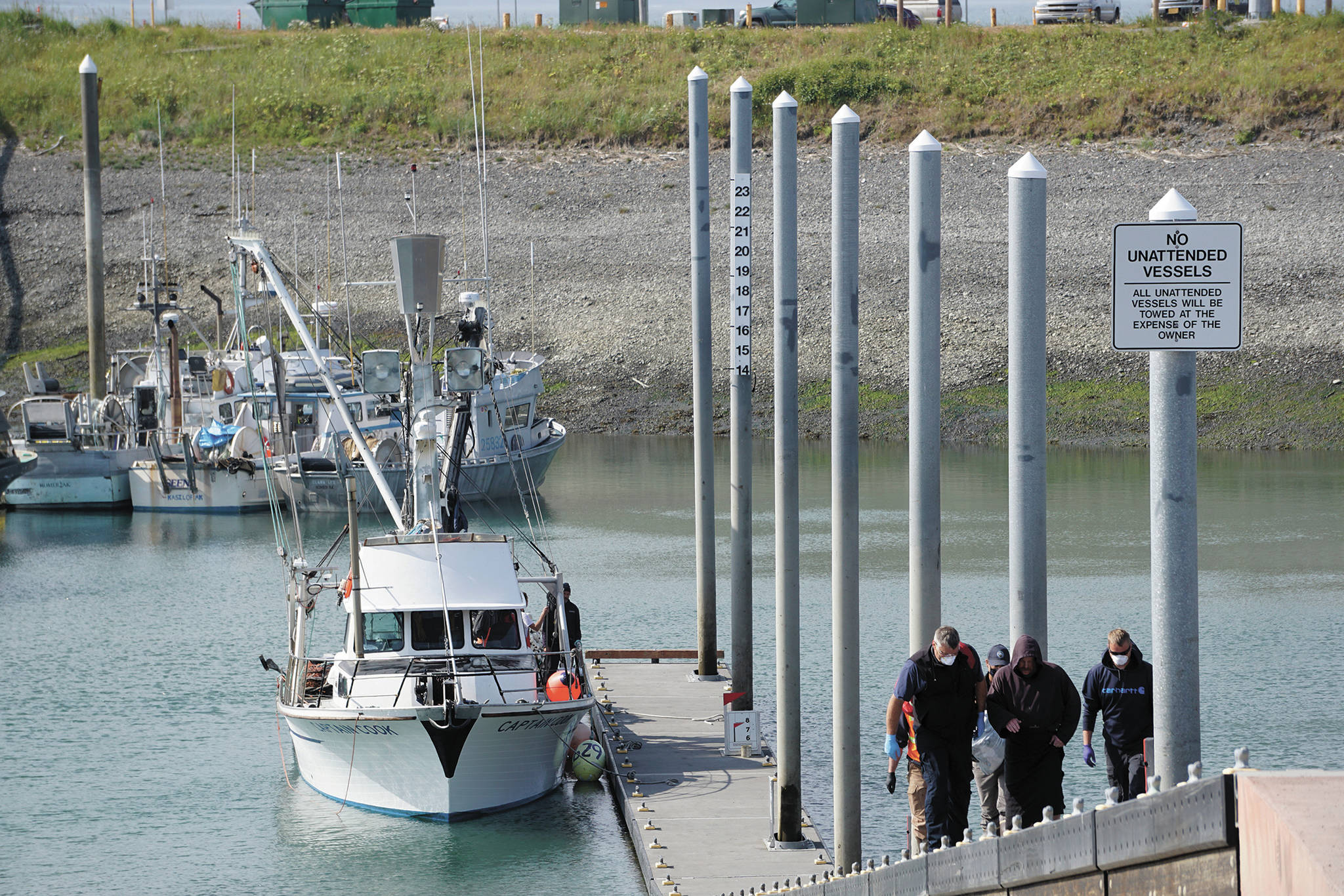 A Homer Volunteer Fire Department emergency medical technician, left, assists a person who was involved in a boat capsizing, center, as they walk up the load-launch ramp on Wednesday, July 8, 2020, at the Homer Harbor in Homer, Alaska. The crew of the F/V Captain Cook helped rescue the person. The crew of the F/V Casino rescued the other two people who were aboard the 14-foot skiff when it capsized near the entrance of China Poot Bay. (Photo by Michael Armstrong/Homer News)