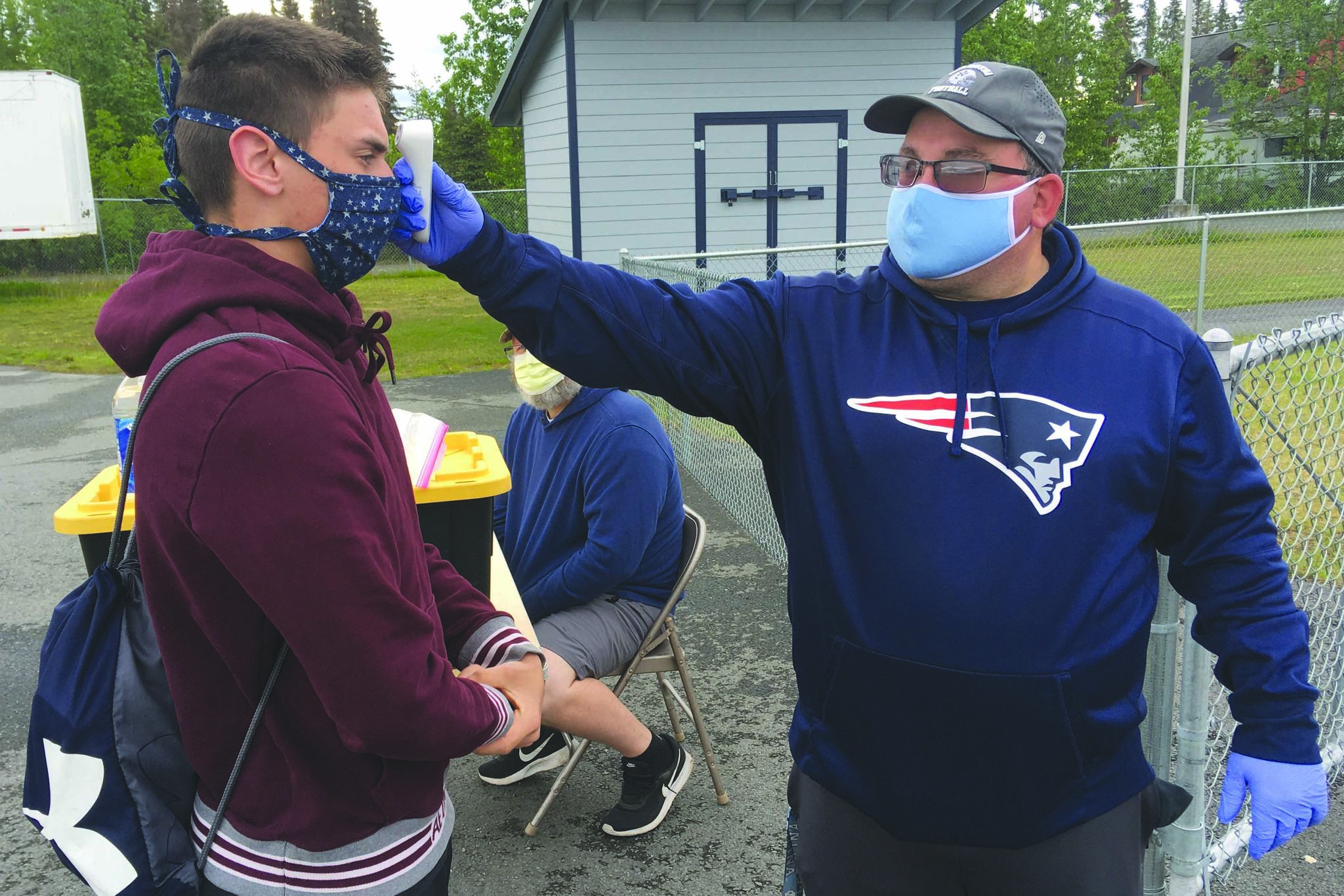 Soldotna assistant football coach Eric Pomerleau checks the temperature of sophomore Joseph Whittom before summer workouts Wednesday, June 17, 2020, at Soldotna High School in Soldotna, Alaska. (Photo by Jeff Helminiak/Peninsula Clarion)