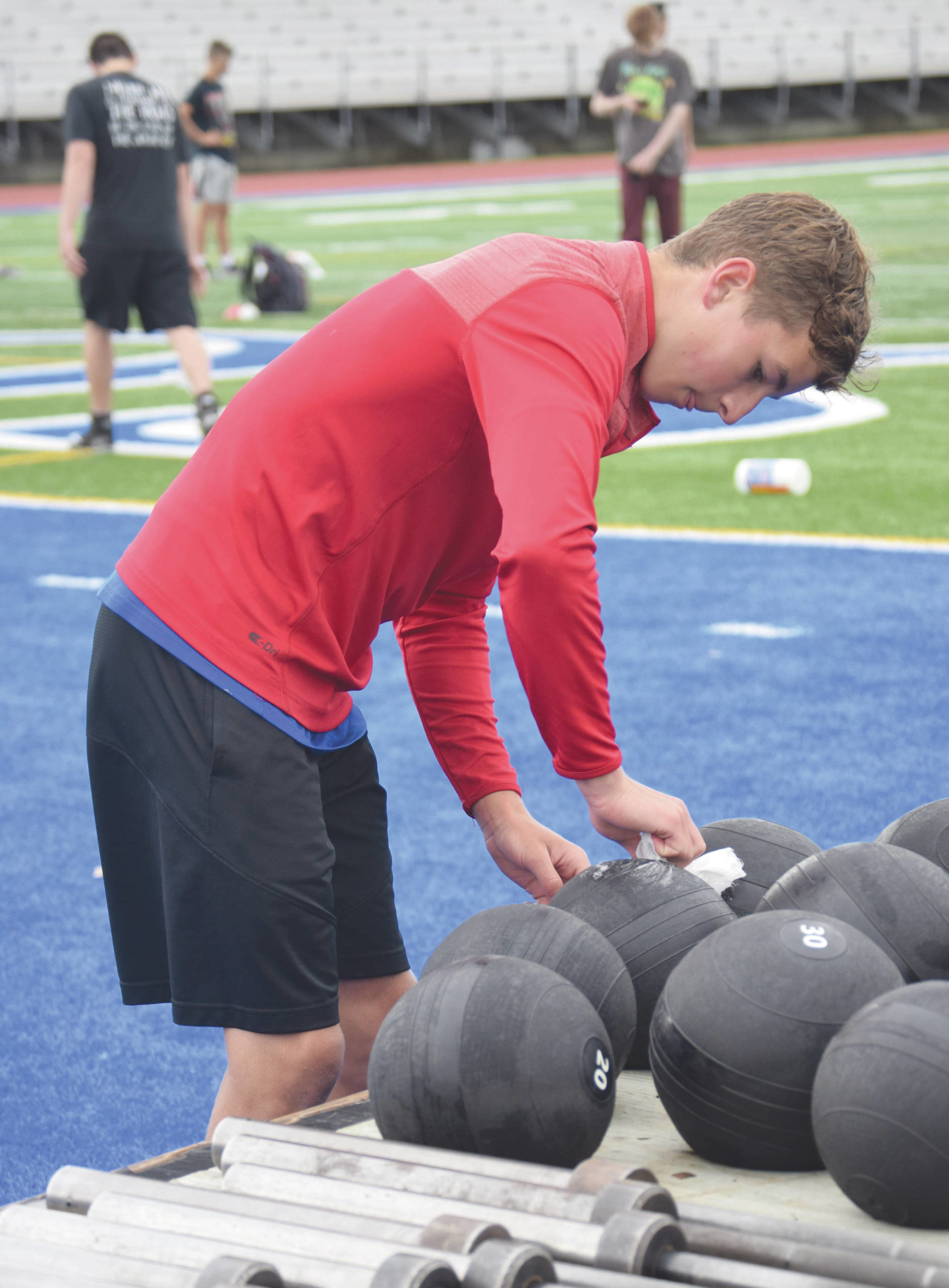 Jeff Helminiak / Peninsula Clarion                                 Soldotna football player Zac Buckbee disinfects a smash ball Wednesday, June 17 at Justin Maile Field in Soldotna.