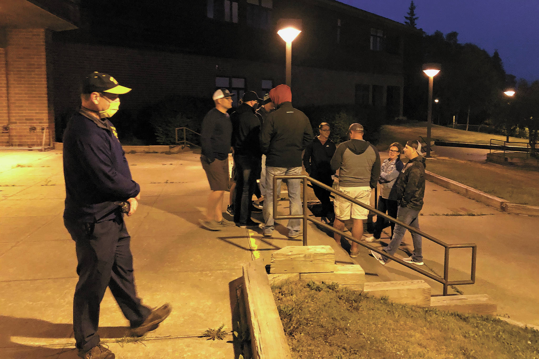 Homer High School Principal Douglas Waclawski (left) stands at the entrance to the local high school while residents show up in search of higher ground in the early morning hours of Wednesday, July 22, 2020 in Homer, Alaska. Homer High School is the designated evacuation location for those below the inundation zone with nowhere else to evacuate to during a tsunami warning. (Photo by Megan Pacer/Homer News)