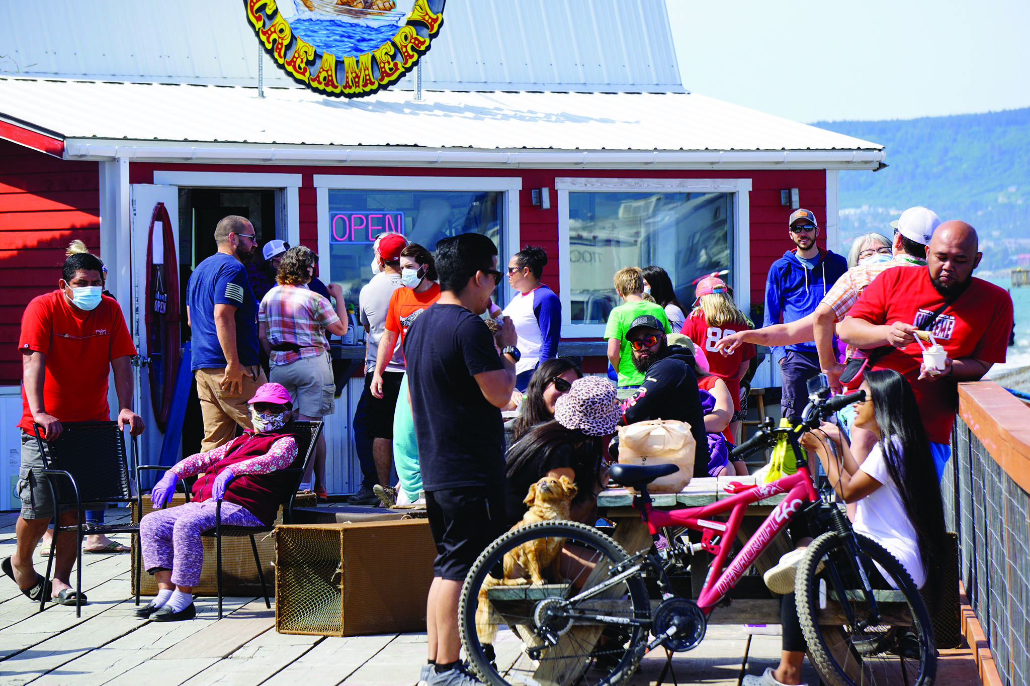 Visitors enjoy the sun on July 4, 2020, on a deck at a Homer Spit boardwalk in Homer, Alaska. In a press conference on Tuesday, July 7, 2020, Alaska Chief Medical Officer Dr. Anne Zink advised people to minimize the risk of getting infected by COVID-19 by avoiding crowded spaces. (Photo by Michael Armstrong/Homer News)