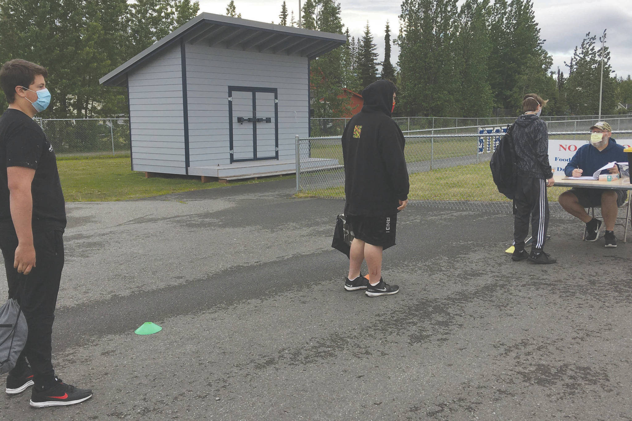 Soldotna football players wait in line to get screened by head coach Galen Brantley Jr. before summer workouts Wednesday, June 17, 2020, at Soldotna High School in Soldotna, Alaska. (Photo by Jeff Helminiak/Peninsula Clarion)