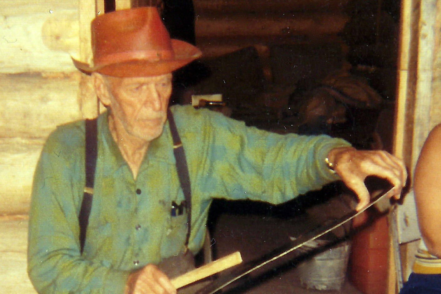 Ed Haun entertains tourists w saw—In this 1972 photo, 87-year-old Ed Haun entertains tourists on his porch with musical abilities on a handsaw. (Courtesy of the Hope and Sunrise Historical Society)
