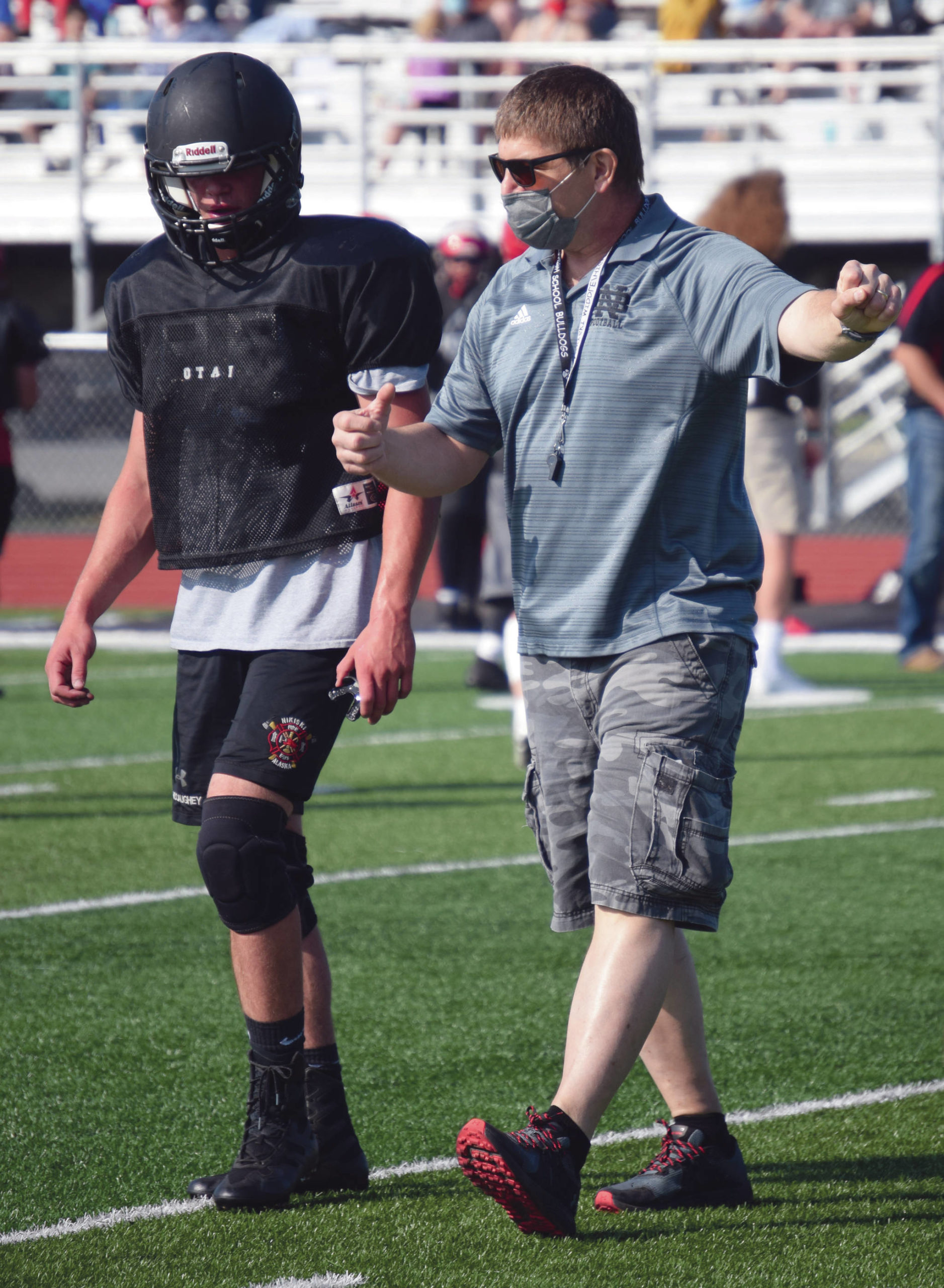 Photo by Jeff Helminiak/Peninsula Clarion                                 Koleman McCaughey talks to Nikiski assistant football coach Tim Johnson on Saturday at the football jamboree at Ed Hollier Field at Kenai Central High School in Kenai, Alaska.