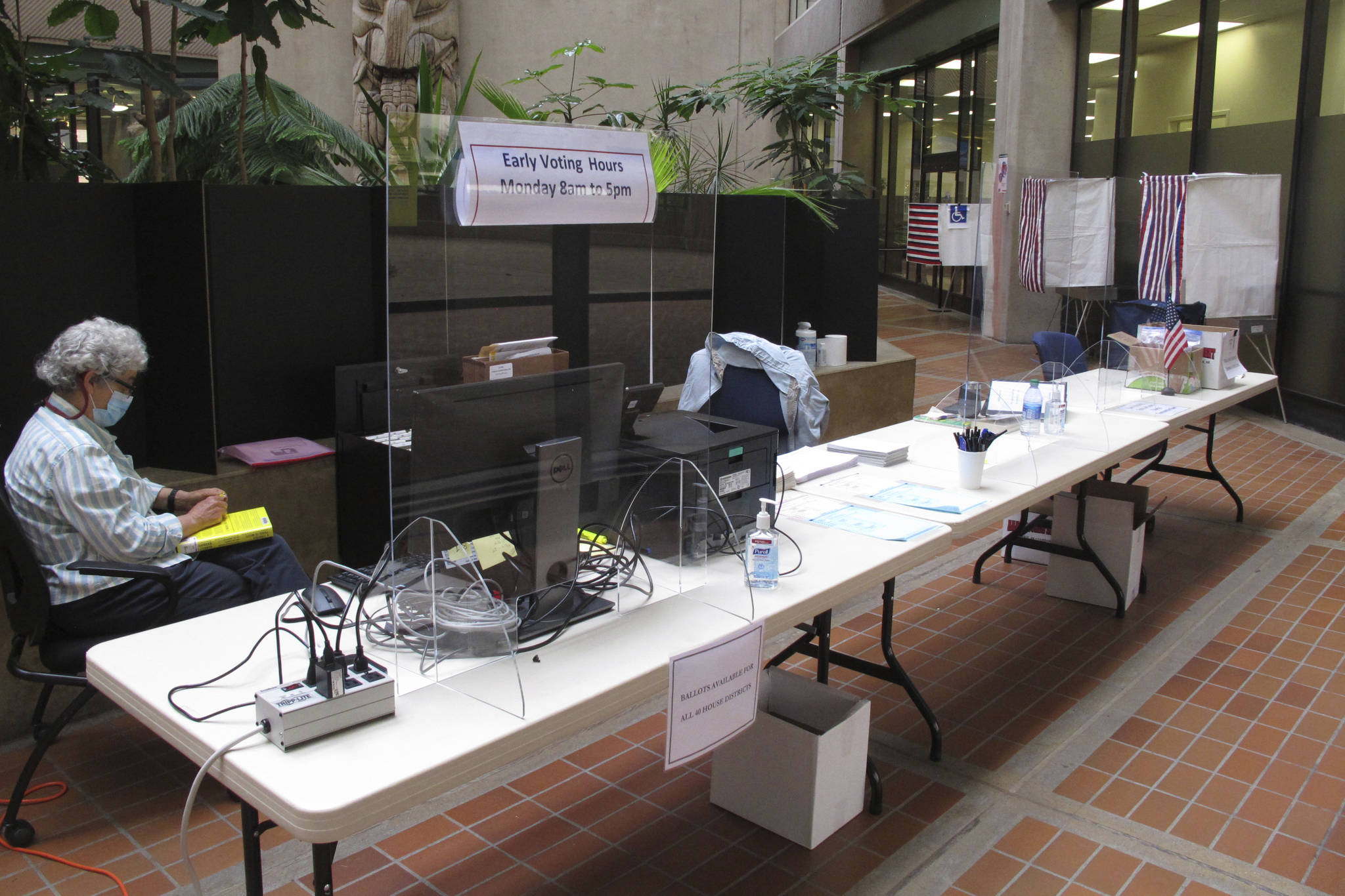 Poll worker Dian Martin minds an early voting site in a state office building in Juneau, Alaska, on Tuesday, Aug. 11, 2020. Voting in Alaska will look a bit different amid the coronavirus pandemic, with election officials saying poll workers will be required to wear protective gear, such as masks, and will encourage voters to maintain social distance and wear masks. (AP Photo/Becky Bohrer)