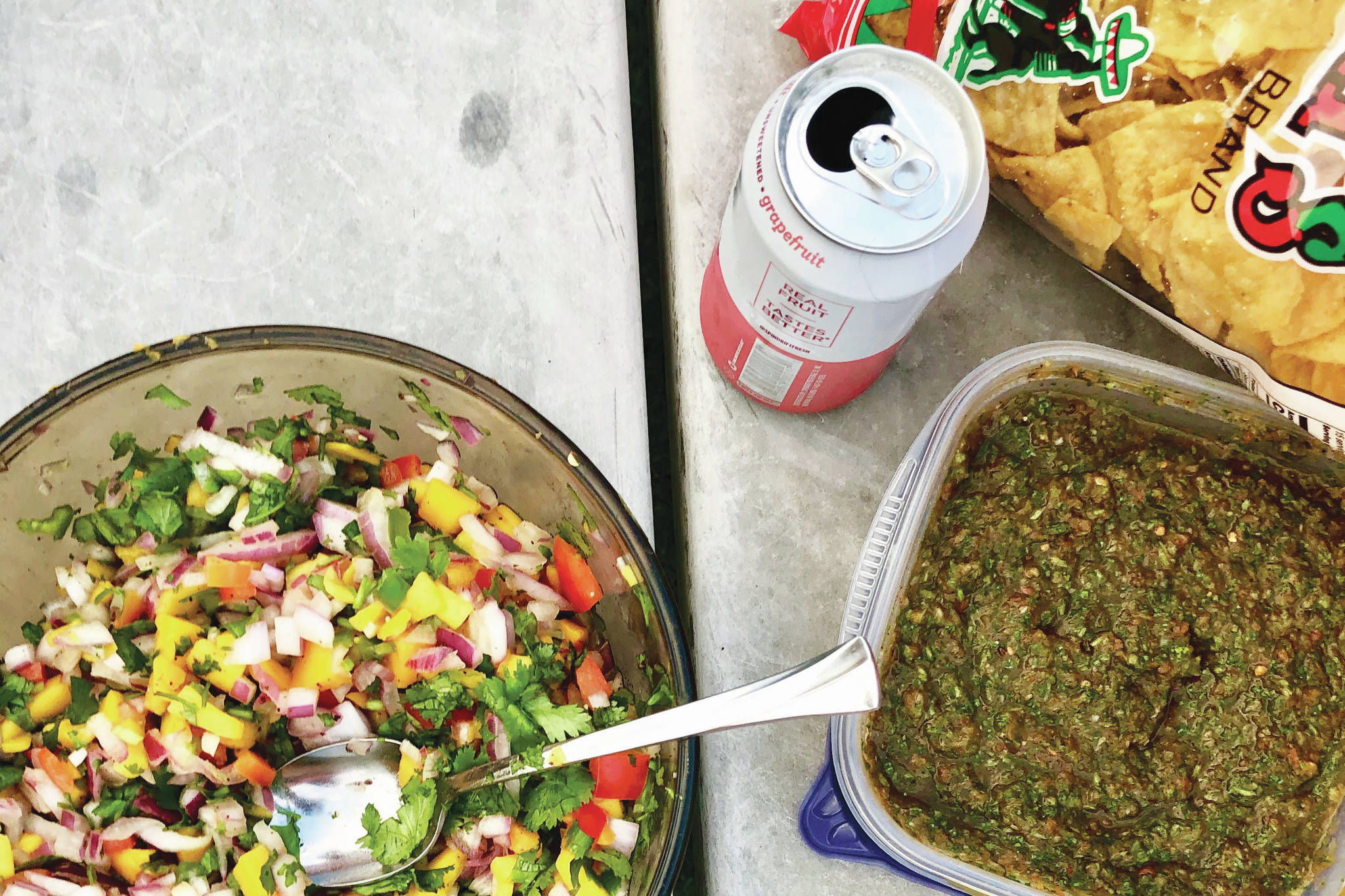 A bowl of mango salsa, next to a bowl of salsa verde, are accompanied by seltzer water, tortilla chips and a shrimp tacos birthday meal on Aug. 21, 2020 in Anchorage, Alaska. (Photo by Victoria Petersen/Peninsula Clarion)