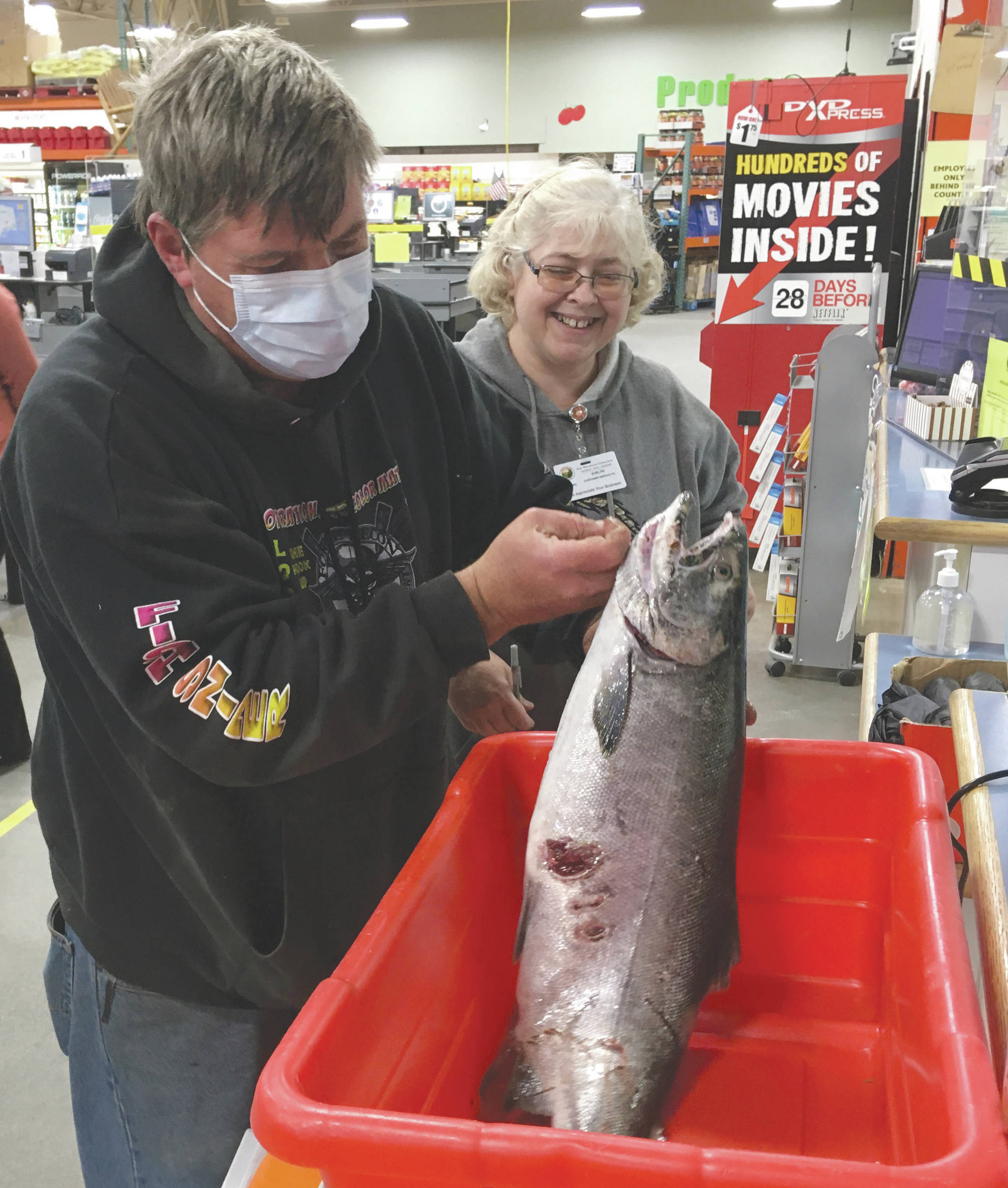 Soldotna’s Errol Severson weighs his fish Tuesday, Sept. 15, 2020, in the Fourth Annual Kenai Silver Salmon Derby at Three Bears in Kenai, Alaska. Evelyn McCoy, customer service PIC at Three Bears, looks on. (Photo by Jeff Helminiak/Peninsula Clarion)