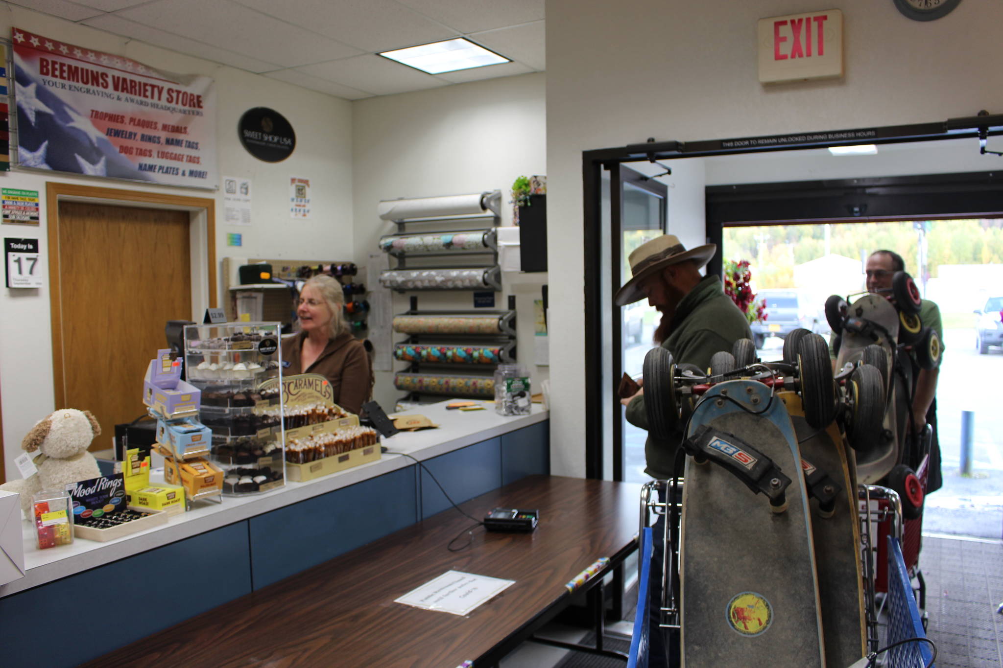 Noah Procter, center, and Brad Carver, right, of Solid Rock Bible Camp, pick up a set of newly repaired mountain boards from Beemuns Variety Ski and Bike Loft as Gaile Sutton, left, rings up the transaction in Soldotna, Alaska on Sept. 17, 2020. (Photo by Brian Mazurek/Peninsula Clarion)