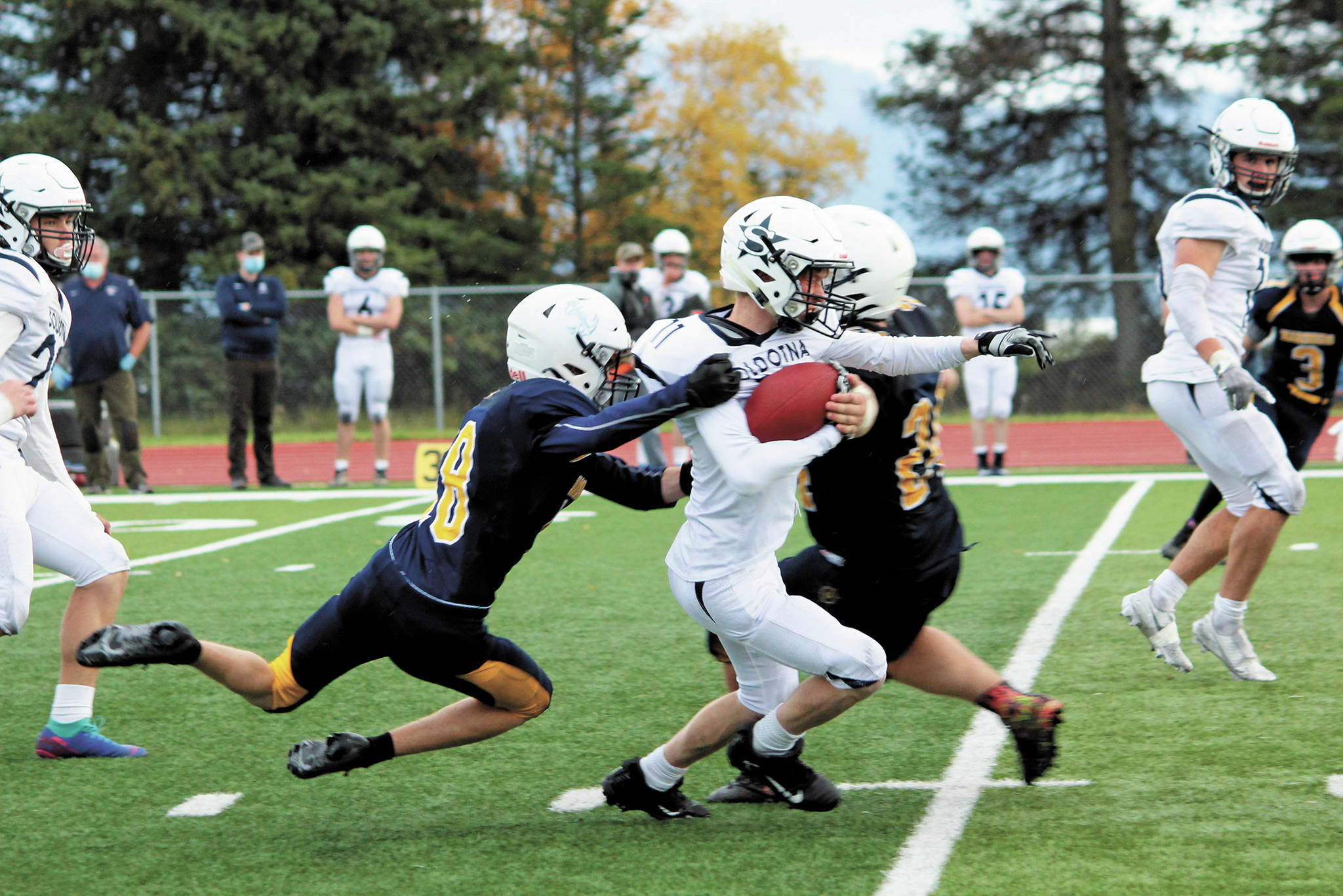 Homer’s Sly Gaona (No. 8) and Kamdyn Doughty (No. 24) tackle Soldotna’s Hunter Secor during a Saturday, Oct. 3, 2020 football game at Homer High School in Homer, Alaska. (Photo by Megan Pacer/Homer News)