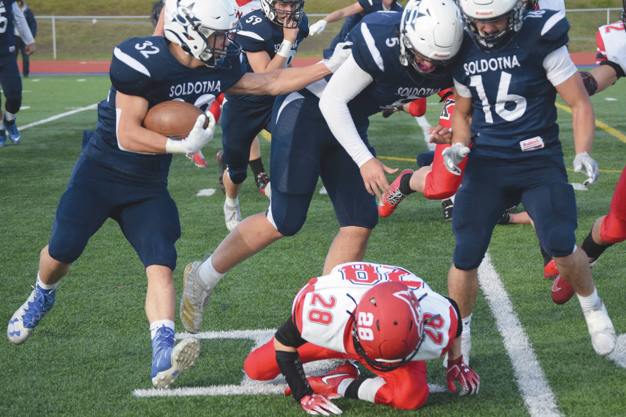 Soldotna’s Dennis Taylor follows the blocking of Brock Wilson and Austin Escott past Kenai Central’s James Sparks on Friday, Oct. 9, 2020, at Justin Maile Field in Kenai, Alaska. (Photo by Jeff Helminiak/Peninsula Clarion)