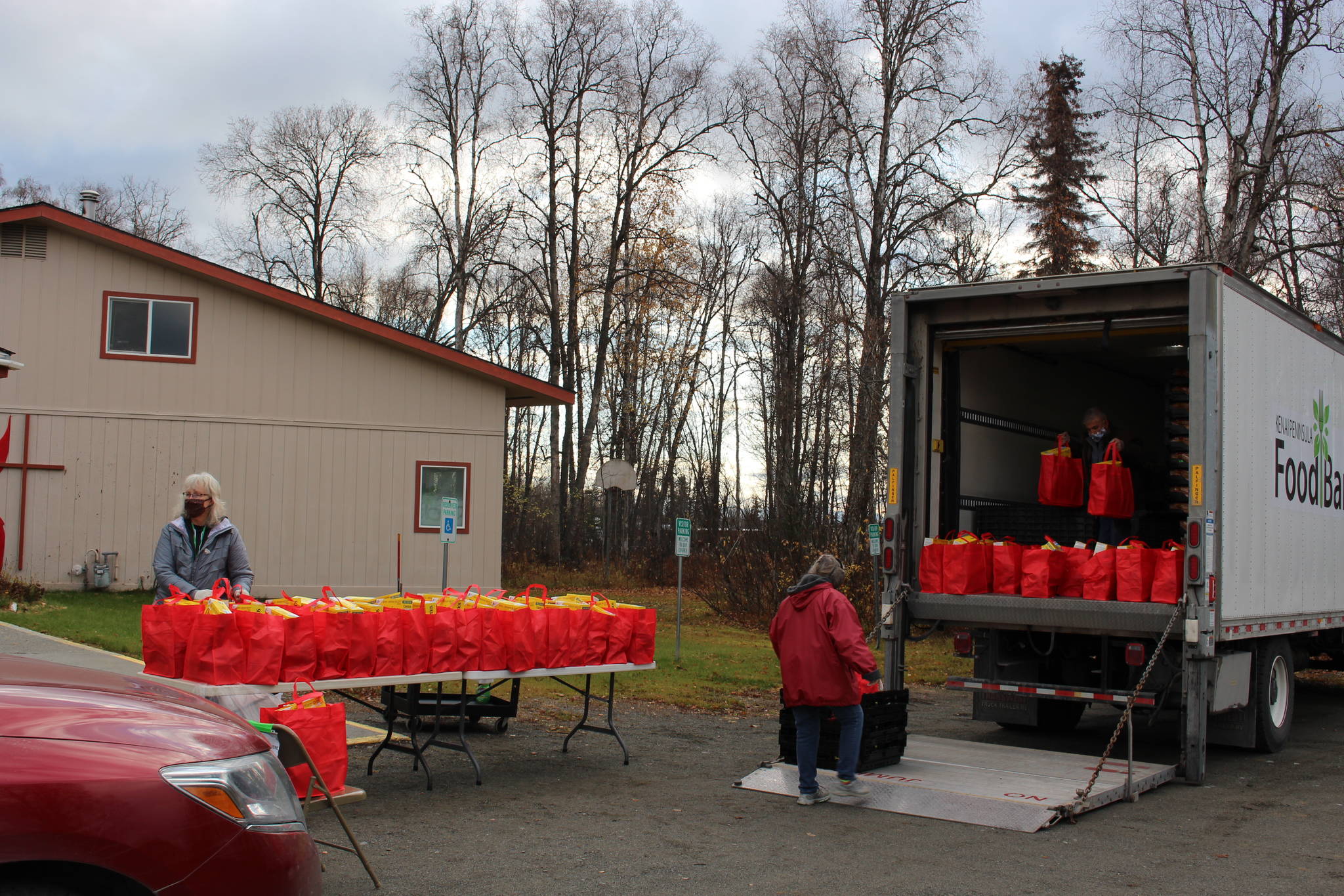 Volunteers distribute bags of food for Soldotna Residents thanks to a grant program from the city at the Soldotna United Methodist Church on Oct. 14, 2020. From left: Cosette Kilfoyle, Director of the Soldotna Food Pantry; Sandy Sandoval and Leroy Sandoval, Food Bank Volunteers. (Photo by Brian Mazurek/Peninsula Clarion)