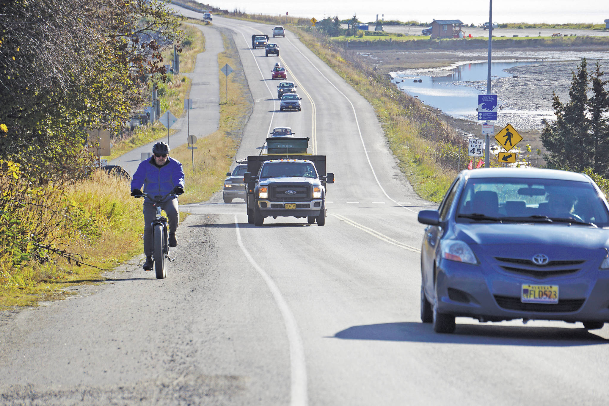 A biker leads a line of cars driving off the Homer Spit at about 1:30 p.m. Monday, Oct. 19, 2020, in Homer, Alaska after a tsunami evacuation order was issued for low-lying areas in Homer. (Photo by Michael Armstrong/Homer New)