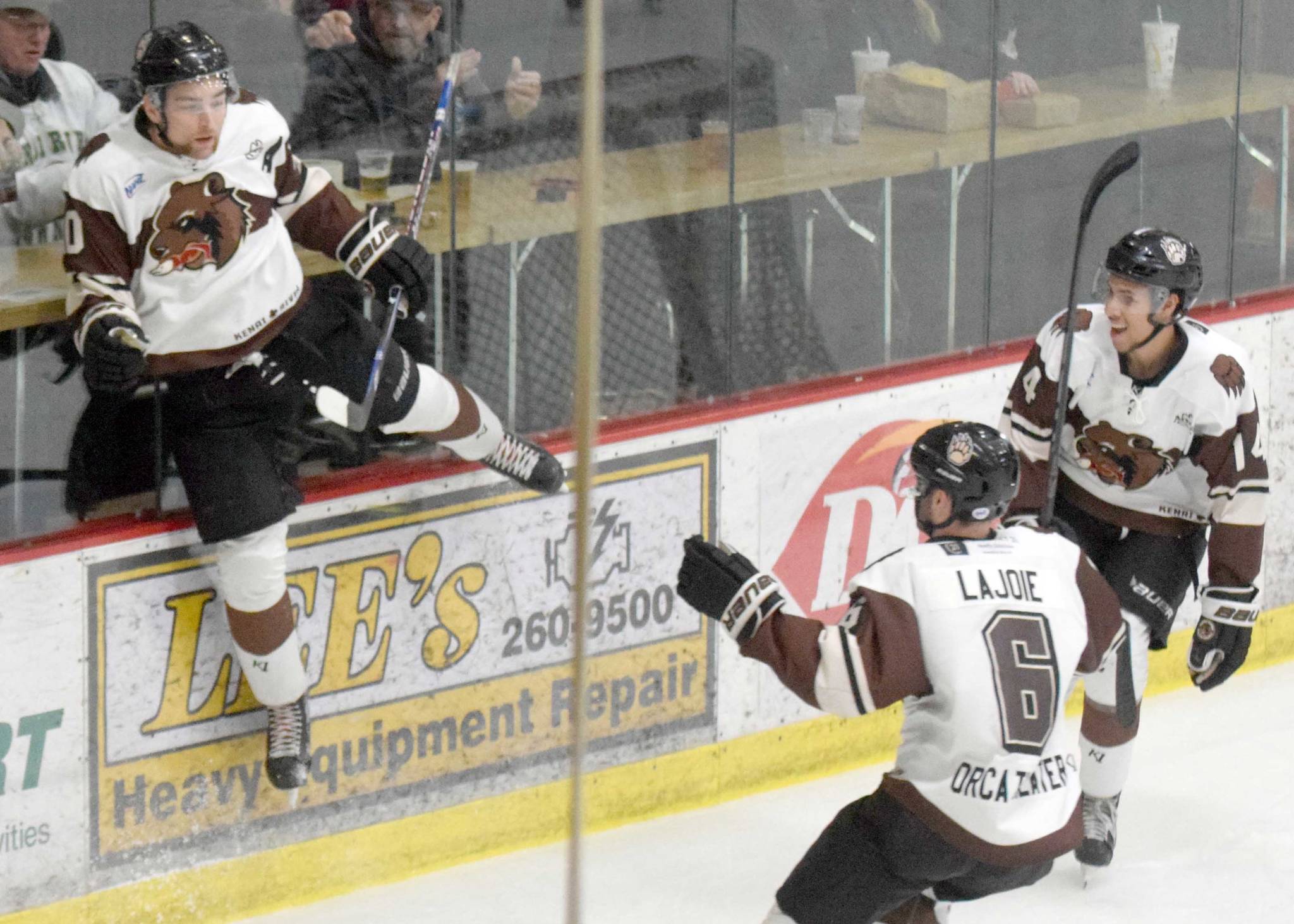 Kenai River Brown Bears forward Laudon Poellinger jumps on the boards to celebrate his first-period goal against the Fairbanks Ice Dogs with Brandon Lajoie and Ryan Reid at the Soldotna Sports Center in Soldotna, Alaska. (Photo by Jeff Helminiak/Peninsula Clarion)