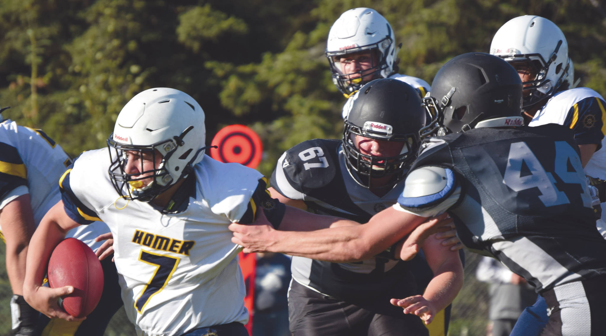 Homers Carter Tennison rushes past Nikiskis Charlie Chamberlain and Koleman McCaughey on Friday, Sept. 11, 2020, at Nikiski High School in Nikiski, Alaska. (Photo by Jeff Helminiak/Peninsula Clarion)