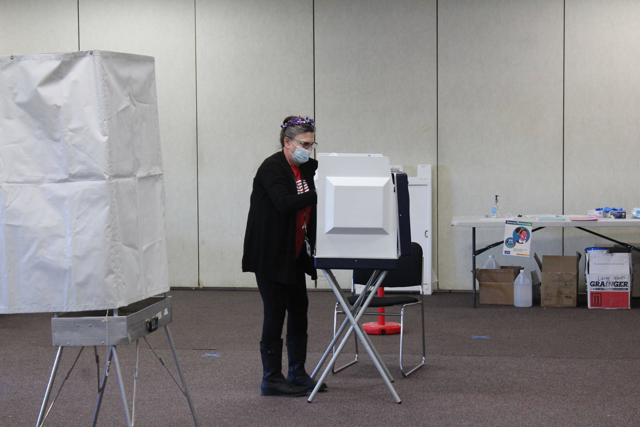 A poll worker is seen disinfecting a voting booth at the Soldotna Regional Sports Complex on Tuesday, Nov. 3 in Soldotna, Alaska. (Photo by Ashlyn O’Hara/Peninsula Clarion)