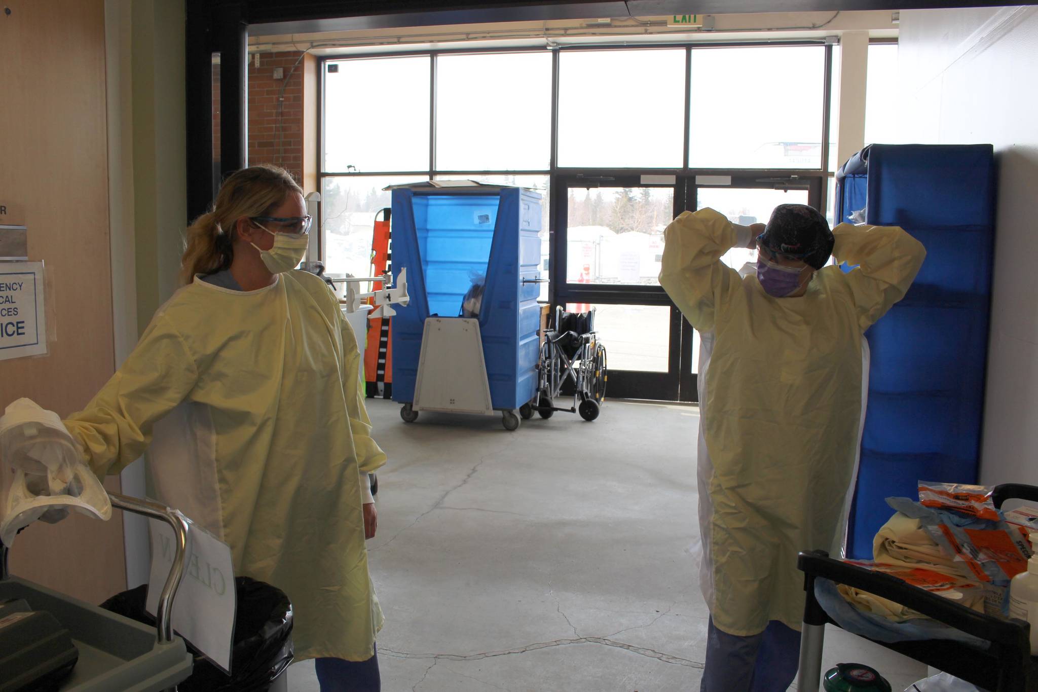 Emergency room technician Angie Sulley, left, and nurse Marcie Duncan put on the personal protective equipment necessary for interacting with patients suspected of having COVID-19 in the ambulance bay outside of the emergency department at Central Peninsula Hospital in Soldotna, Alaska on April 7, 2020. (Photo by Brian Mazurek/Peninsula Clarion)