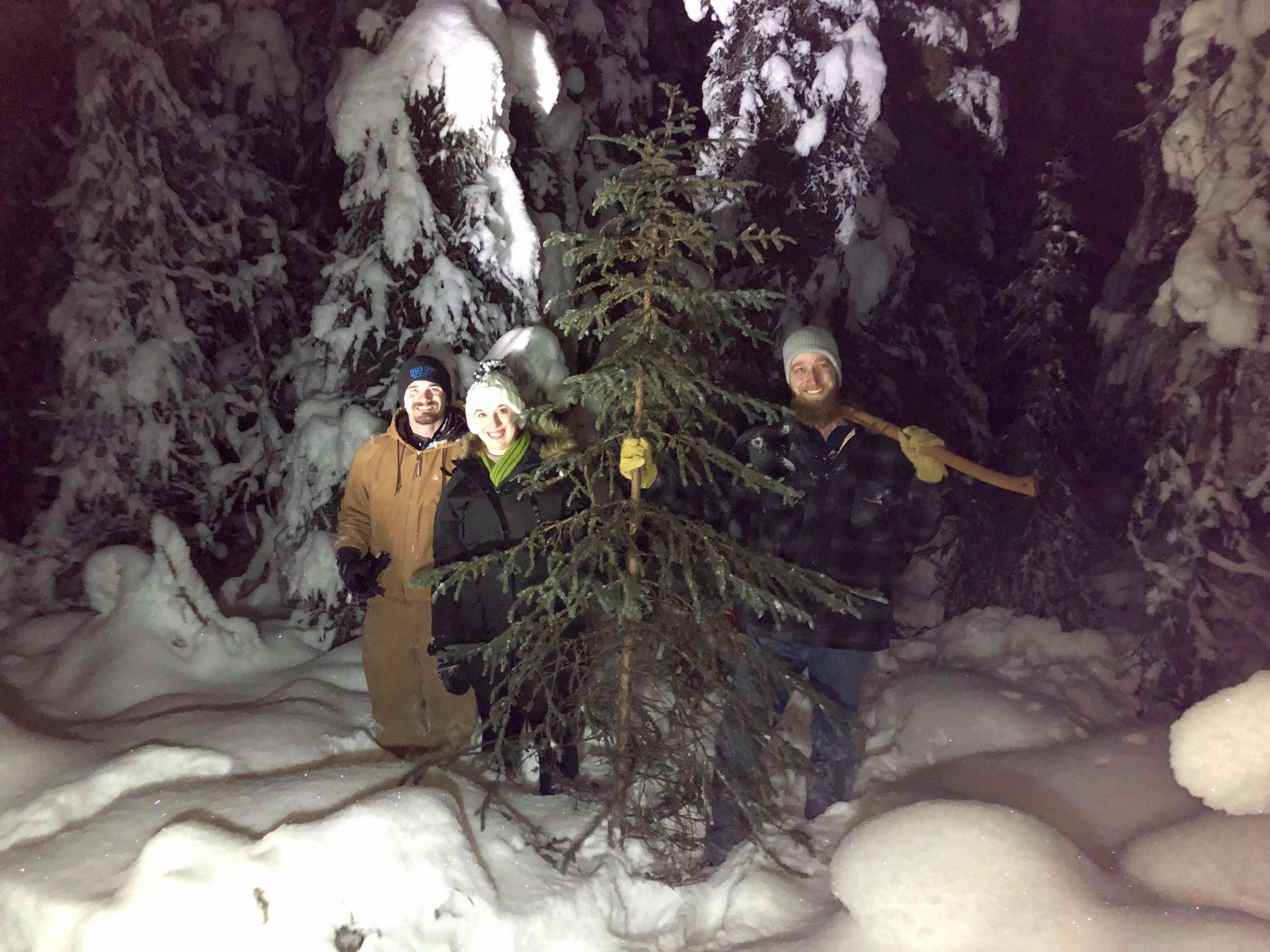 Ben Weagraff, Olivia Orth and Brian Mazurek stand next to a freshly cut black spruce off Funny River Road in Soldotna, Alaska on Dec. 8, 2019. (Photo by Victoria Peterson)