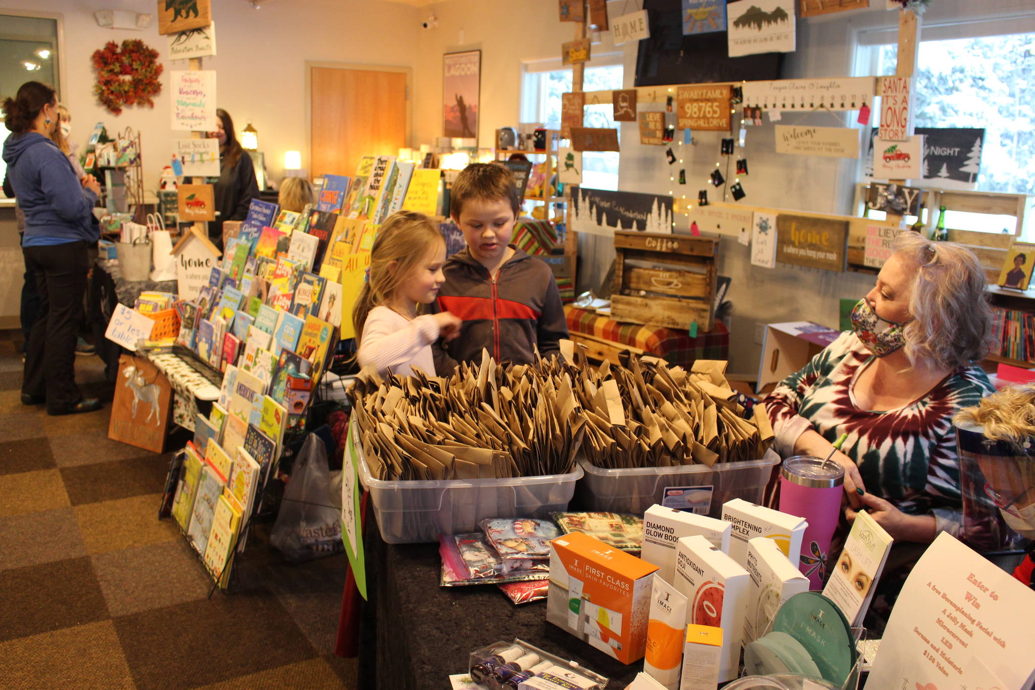 Elizabeth Shaw, left, and Nathaniel Shaw, center, pick out a grab bag in the hopes of winning a free quilt from Karri Ambrosini, right, during the Sterling Fall Festival at the Sterling Community Center on Nov. 28, 2020. (Photo by Brian Mazurek/Peninsula Clarion)