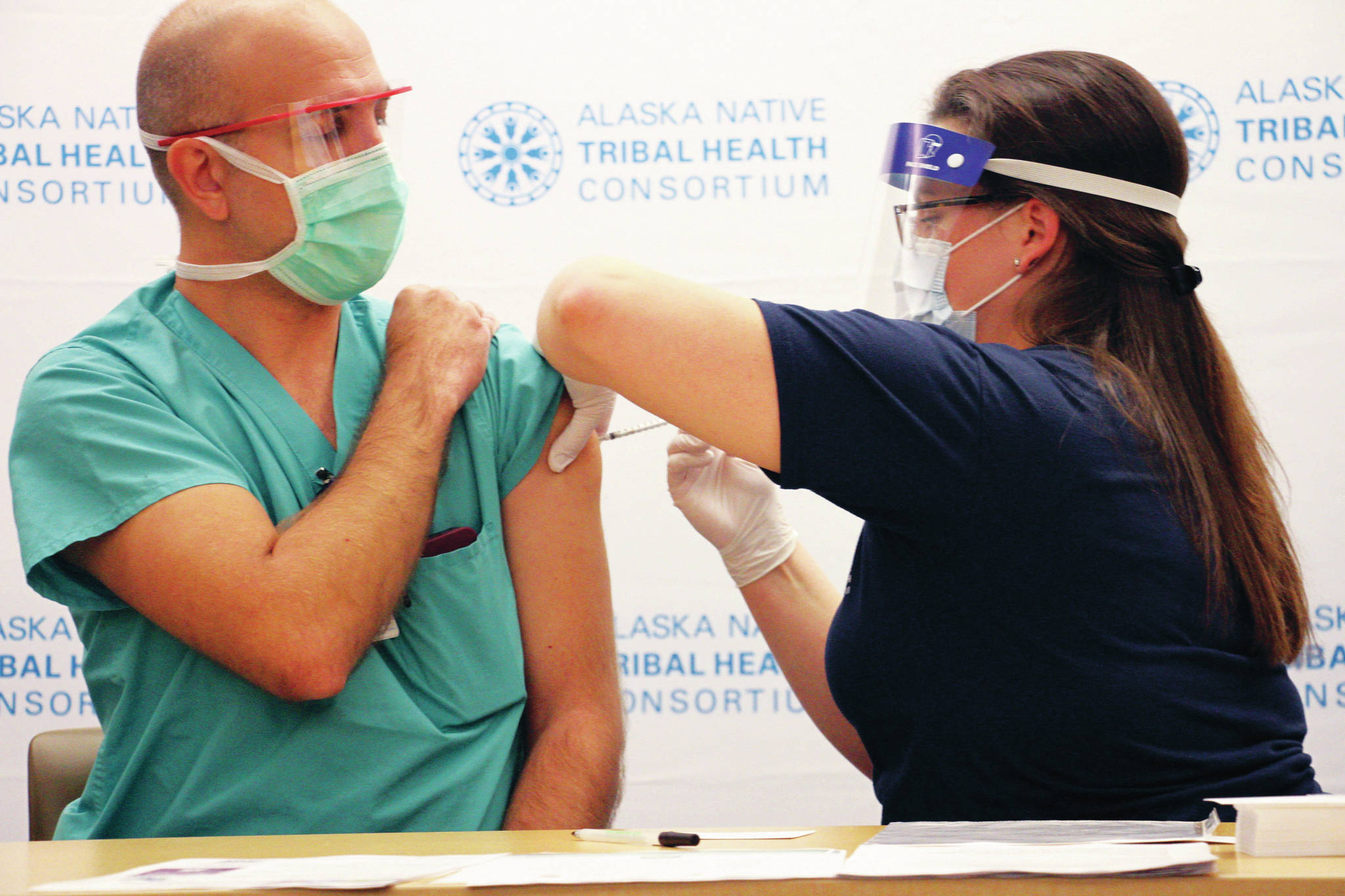 Dr. David Zielke, left, a pulmonary critical care physician, receives a dose of COVID-19 vaccine from Emily Schubert, the employee health nurse at the Alaska Native Medical Center in Anchorage, Alaska, on Tuesday, Dec. 15, 2020. Front-line health care workers are among the first in Alaska to receive the vaccine. (AP Photo/Mark Thiessen)