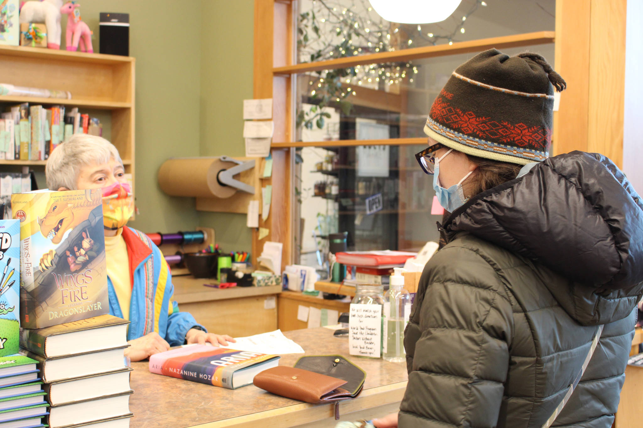 Brian Mazurek/Peninsula Clarion 
Maria Dixson, left, rings up a purchase by Sarah Pyhala, right, at River City Books in Soldotna on Saturday.