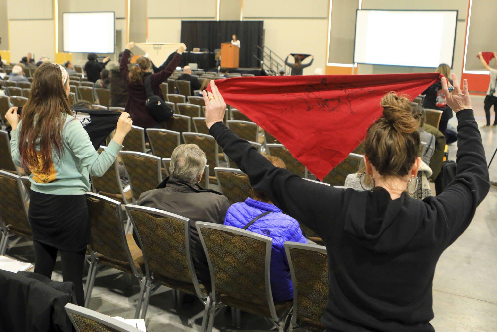 In this Feb. 11, 2019 file photo, protesters hold up flags during a public hearing on a draft environmental plan on proposed petroleum leasing within Alaska’s Arctic National Wildlife Refuge in Anchorage, Alaska. Conservationists will try to persuade a U.S. judge to stop the Trump administration from issuing leases to oil and gas companies in the Arctic National Wildlife Refuge. The Anchorage Daily News reported that the videoconference Monday, Jan. 4, 2021, in U.S. District Court in Anchorage is expected to determine whether the Bureau of Land Management can open bids in an online lease sale scheduled for Wednesday. The agency has offered 10-year leases on 22 tracts covering about 1,563 square miles in the coastal plain, which accounts for about 5% of the refuge’s area. (AP Photo/Dan Joling, File)
