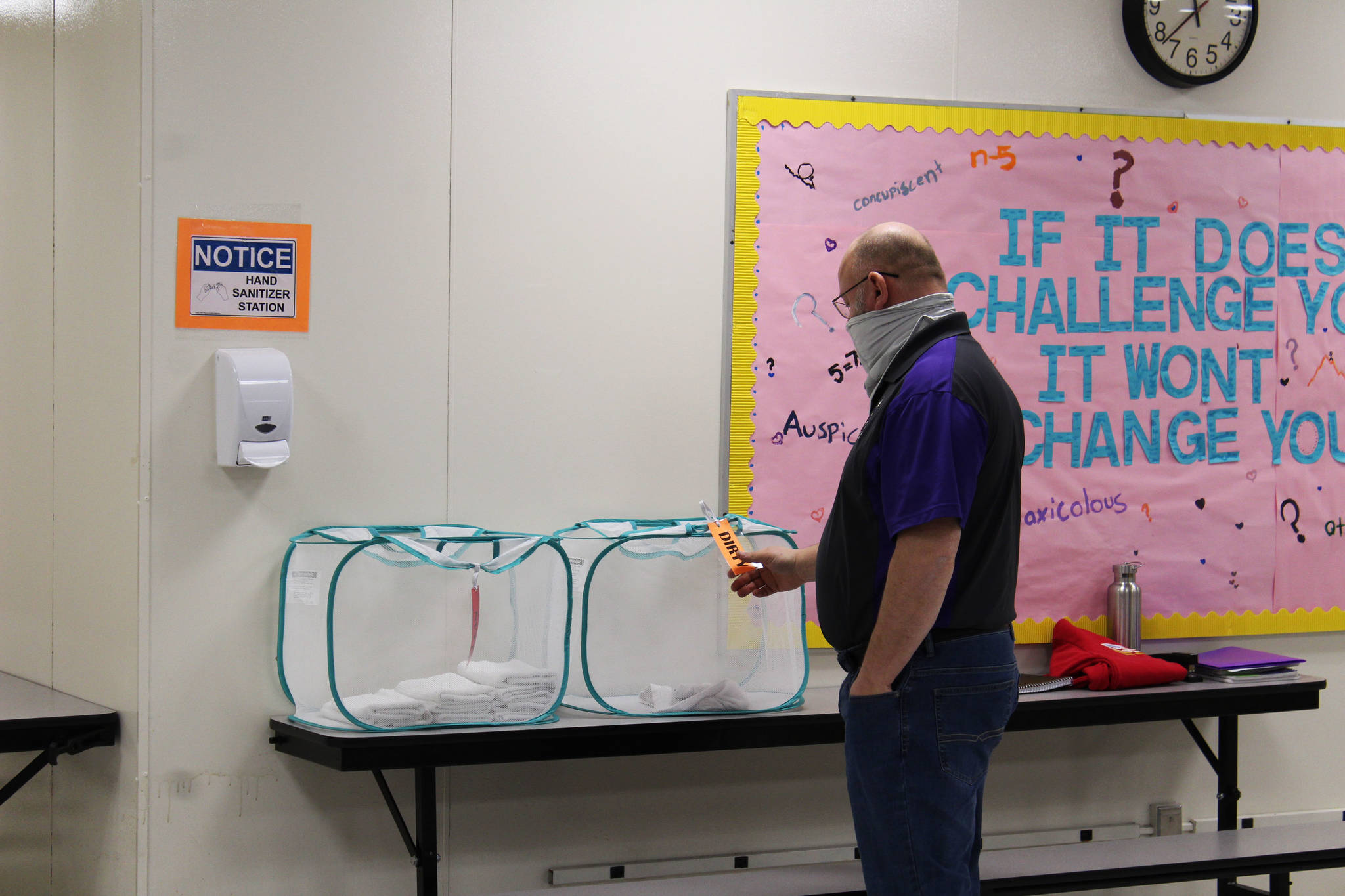 Vaughn Dosko adjusts a basket for sanitizing rags at Kenai Middle School on Friday, Jan. 8 in Kenai, Alaska. (Ashlyn O’Hara/Peninsula Clarion)