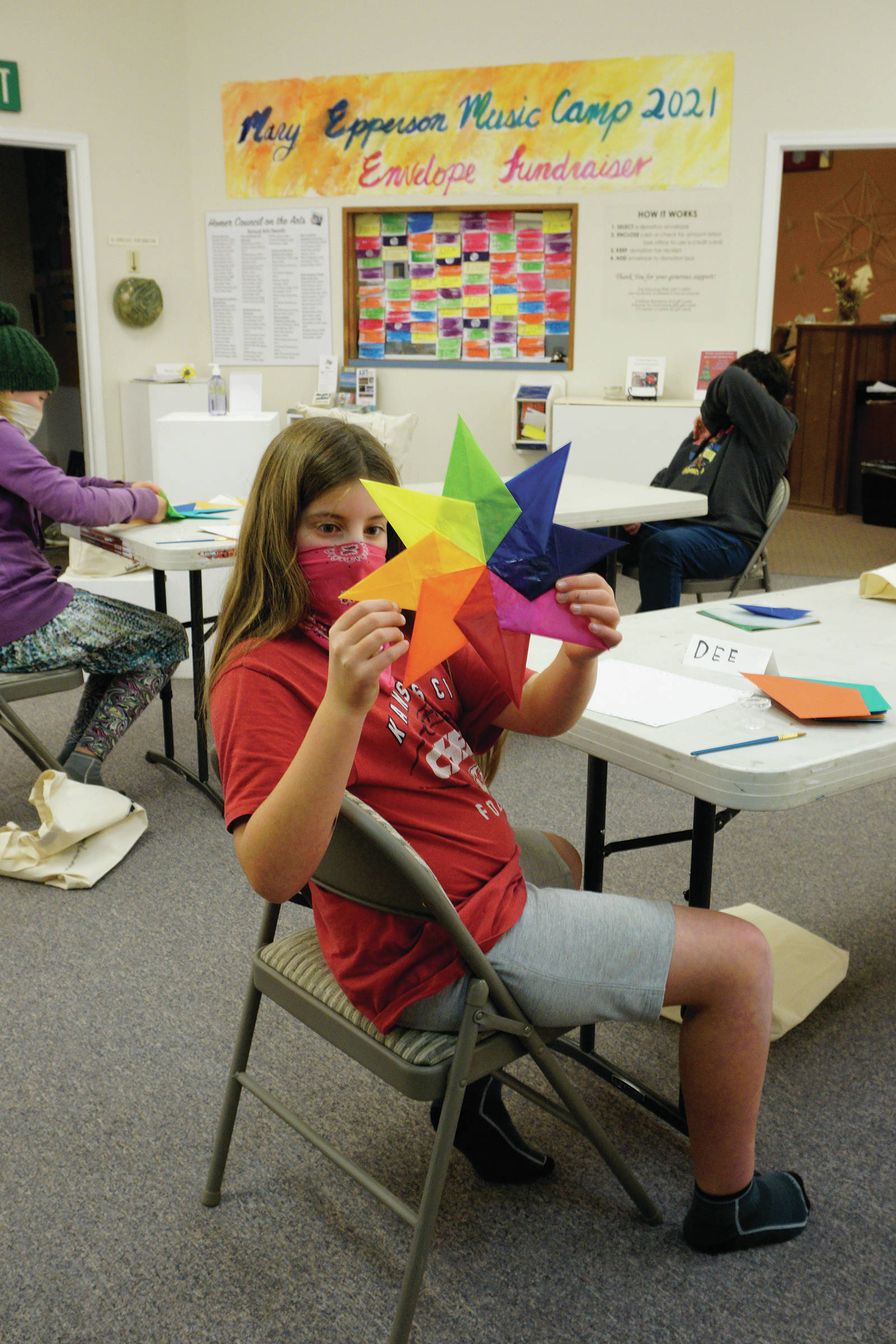 Dee Wilmeth, age 9, shows an origami star she made in Amy Komar’s socially-distant Art a la Carte class on Friday, Nov. 20, 2020, at the Homer Council on the Arts. Children in the class wore masks and worked at either end of long tables spaced apart. The stars will be placed in store windows “for a dose of color therapy for the community,” Komar said. (Photo by Michael Armstrong/Homer News)