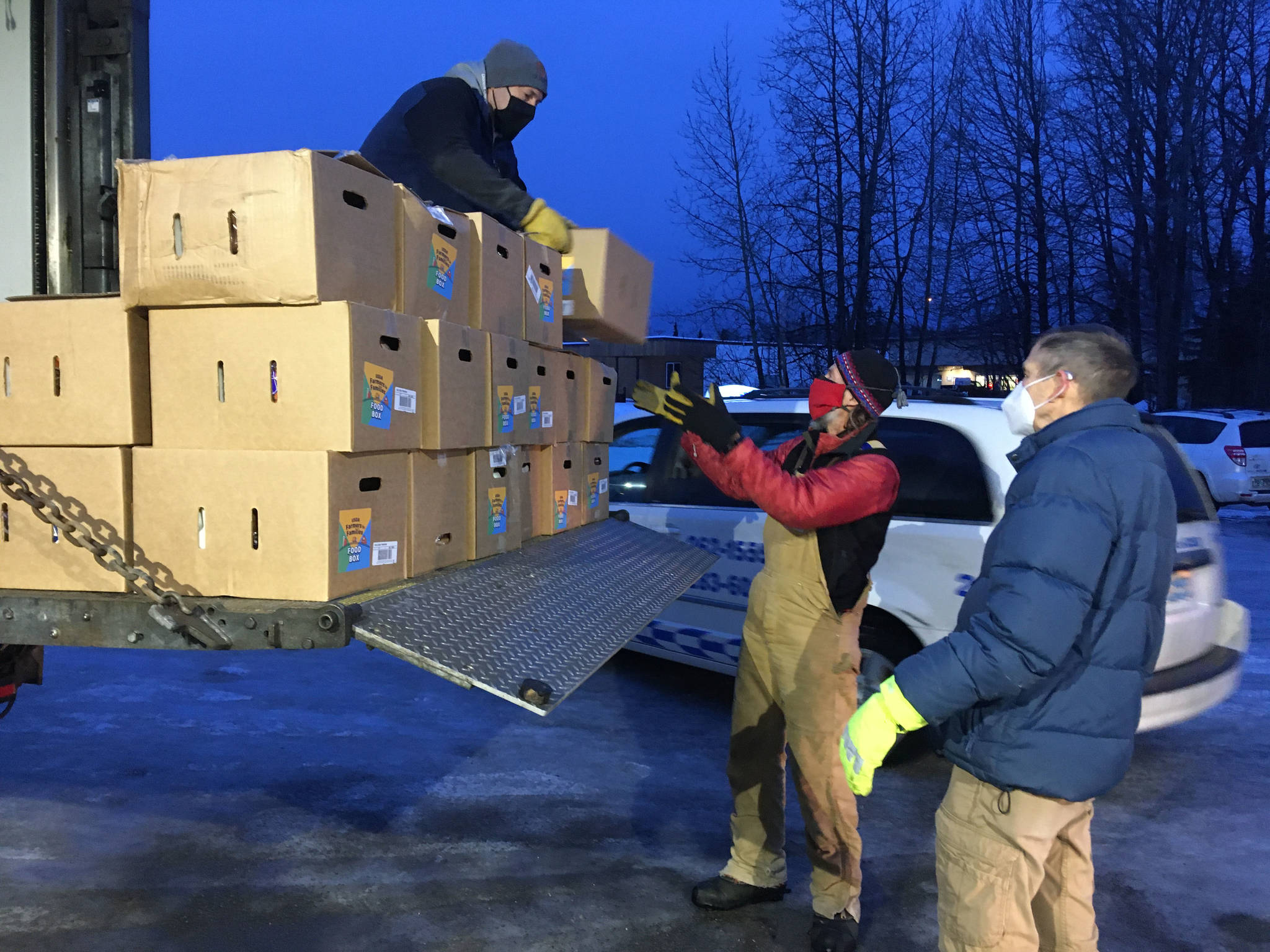 Todd Duwe hands a food box to Brad Nyquist as Mark Larson looks on Tuesday, Dec. 22, 2020, at Christ Lutheran Church in Soldotna, Alaska. The church volunteers were distributing food from the United States’ Department of Agriculture’s Farmers to Families Food Box Program, delivered by the Kenai Peninsula Food Bank. (Photo by Jeff Helminiak/Peninsula Clarion)