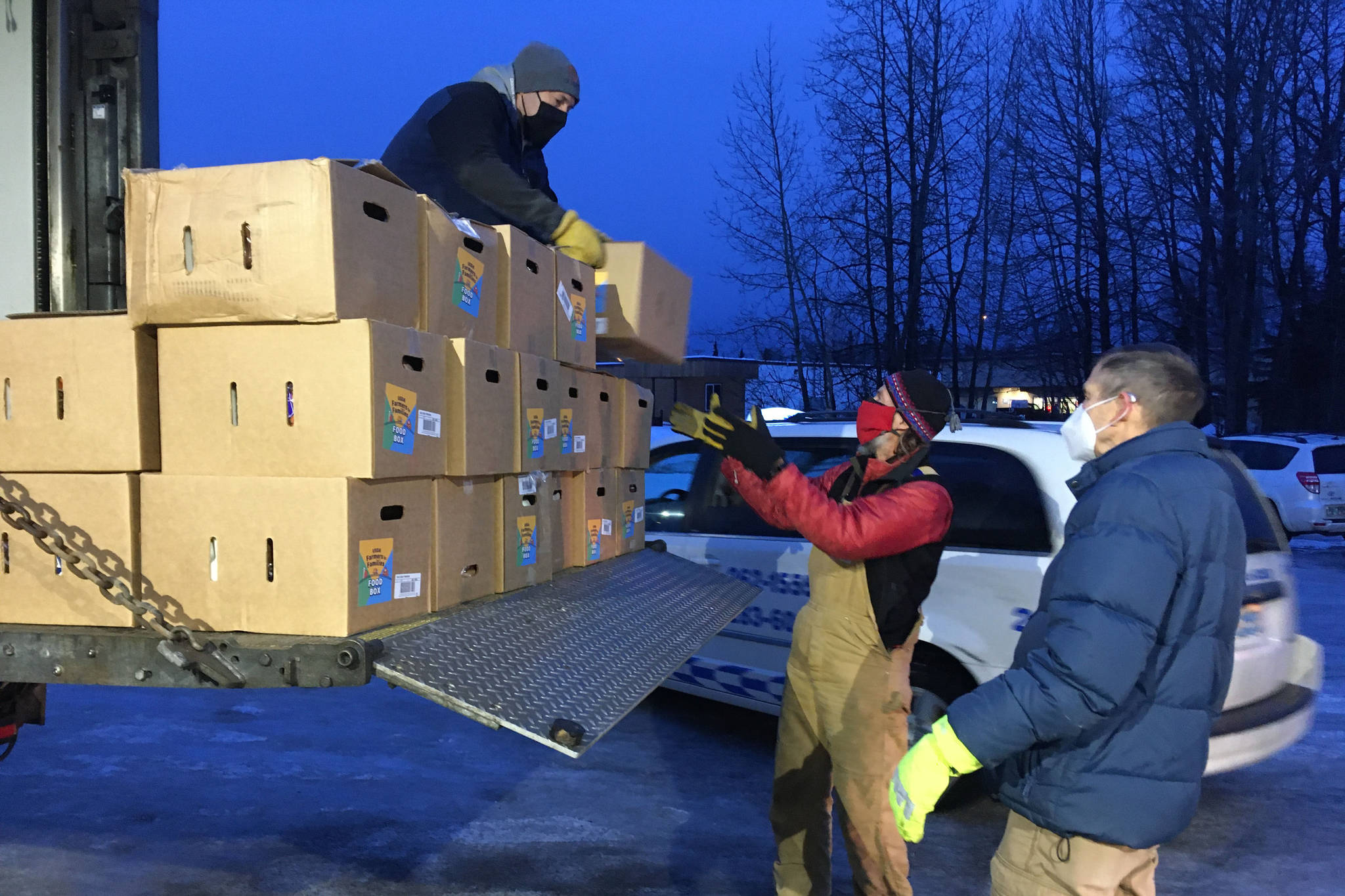 Todd Duwe hands a food box to Brad Nyquist as Mark Larson looks on Tuesday, Dec. 22, 2020, at Christ Lutheran Church in Soldotna, Alaska. The church volunteers were distributing food from the United States’ Department of Agriculture’s Farmers to Families Food Box Program, delivered by the Kenai Peninsula Food Bank. (Photo by Jeff Helminiak/Peninsula Clarion)