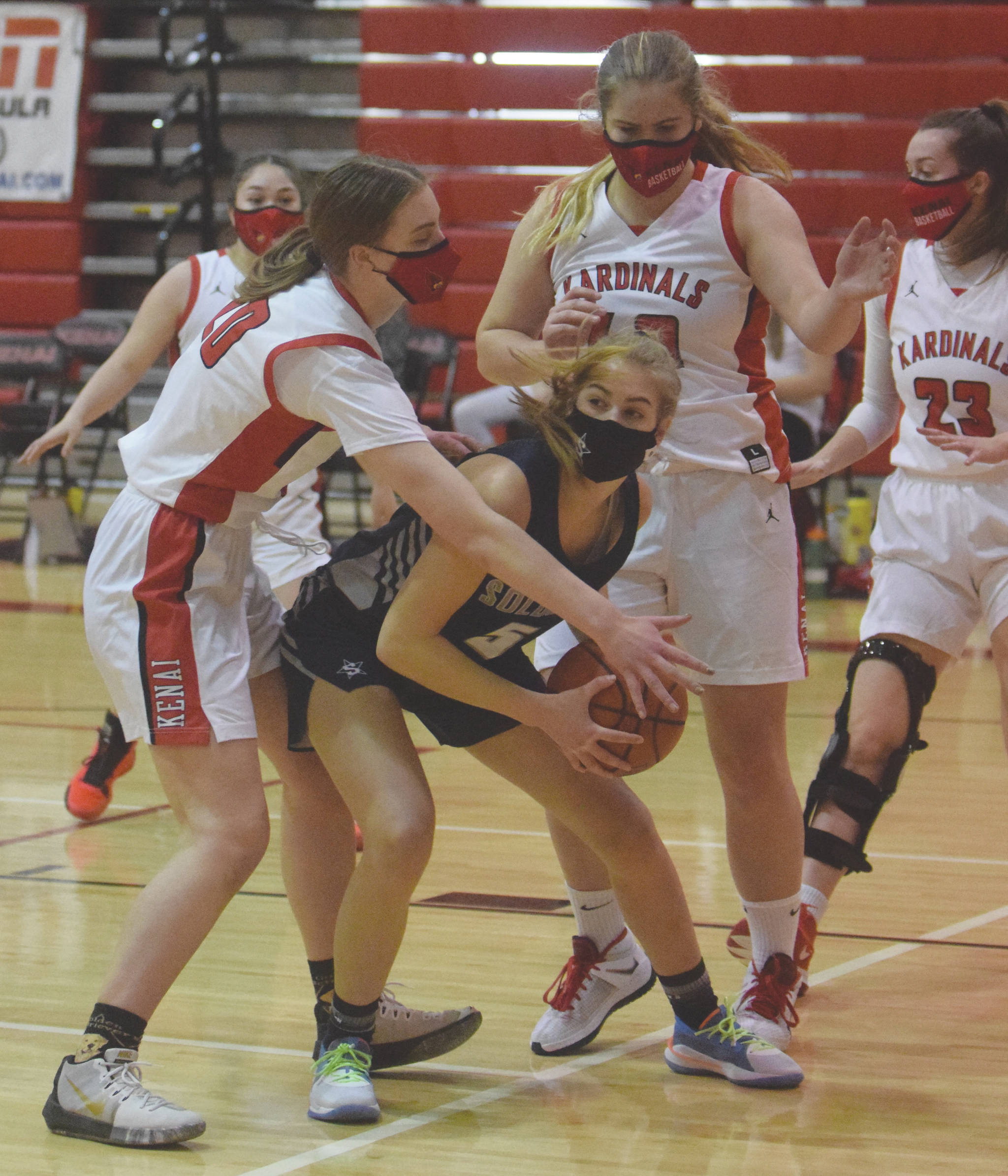 Kenai Central’s Erin Koziczkowski and Emma Beck trap Soldotna’s Montana Fischer on Thursday, Jan. 21, 2021, at Kenai Central High School in Kenai, Alaska. (Photo by Jeff Helminiak/Peninsula Clarion)