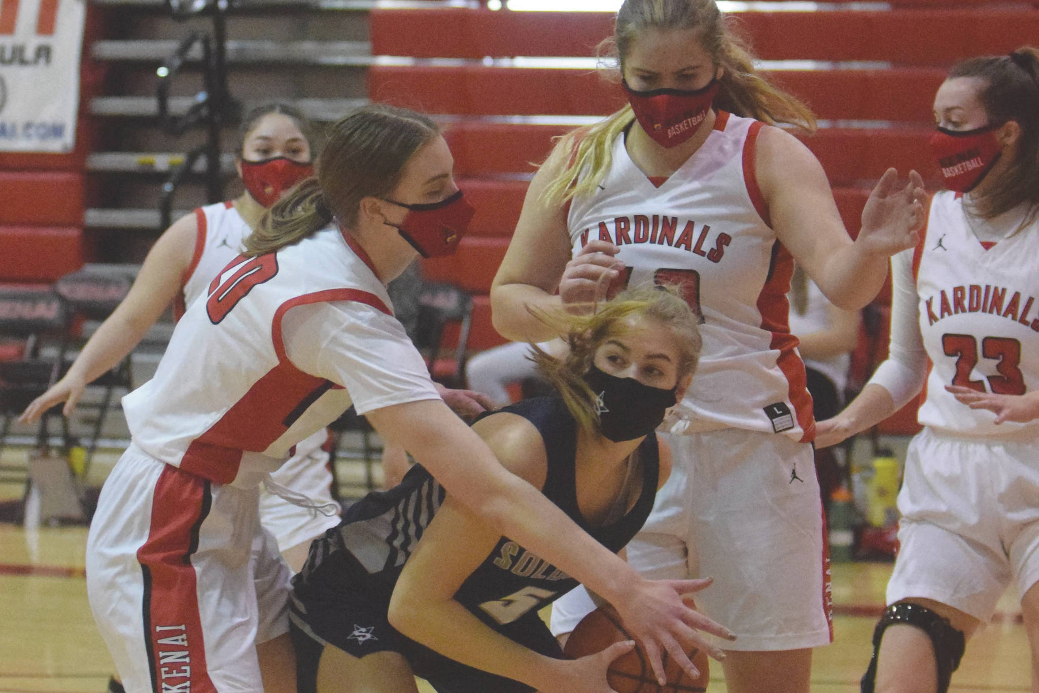 Kenai Central's Erin Koziczkowski and Emma Beck trap Soldotna's Montana Fischer on Thursday, Jan. 21, 2021, at Kenai Central High School in Kenai, Alaska. (Photo by Jeff Helminiak/Peninsula Clarion)