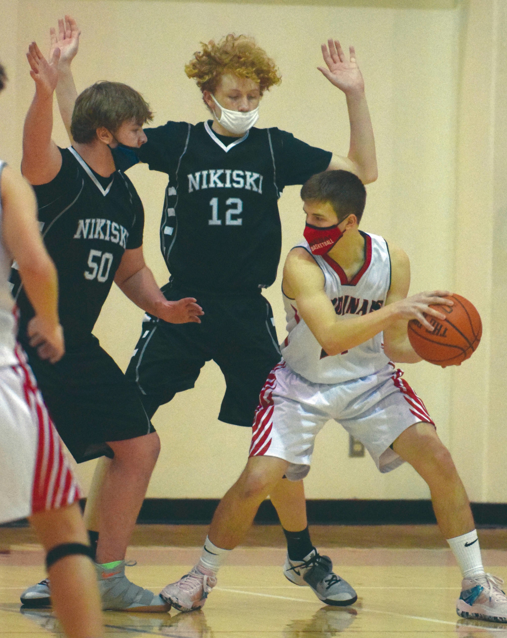 Nikiski’s Drew Handley and Brady Bostic defend Kenai Central’s Bridger Beck on Saturday, Jan. 23, 2021, at Kenai Central High School in Kenai, Alaska. (Photo by Jeff Helminiak/Peninsula Clarion)